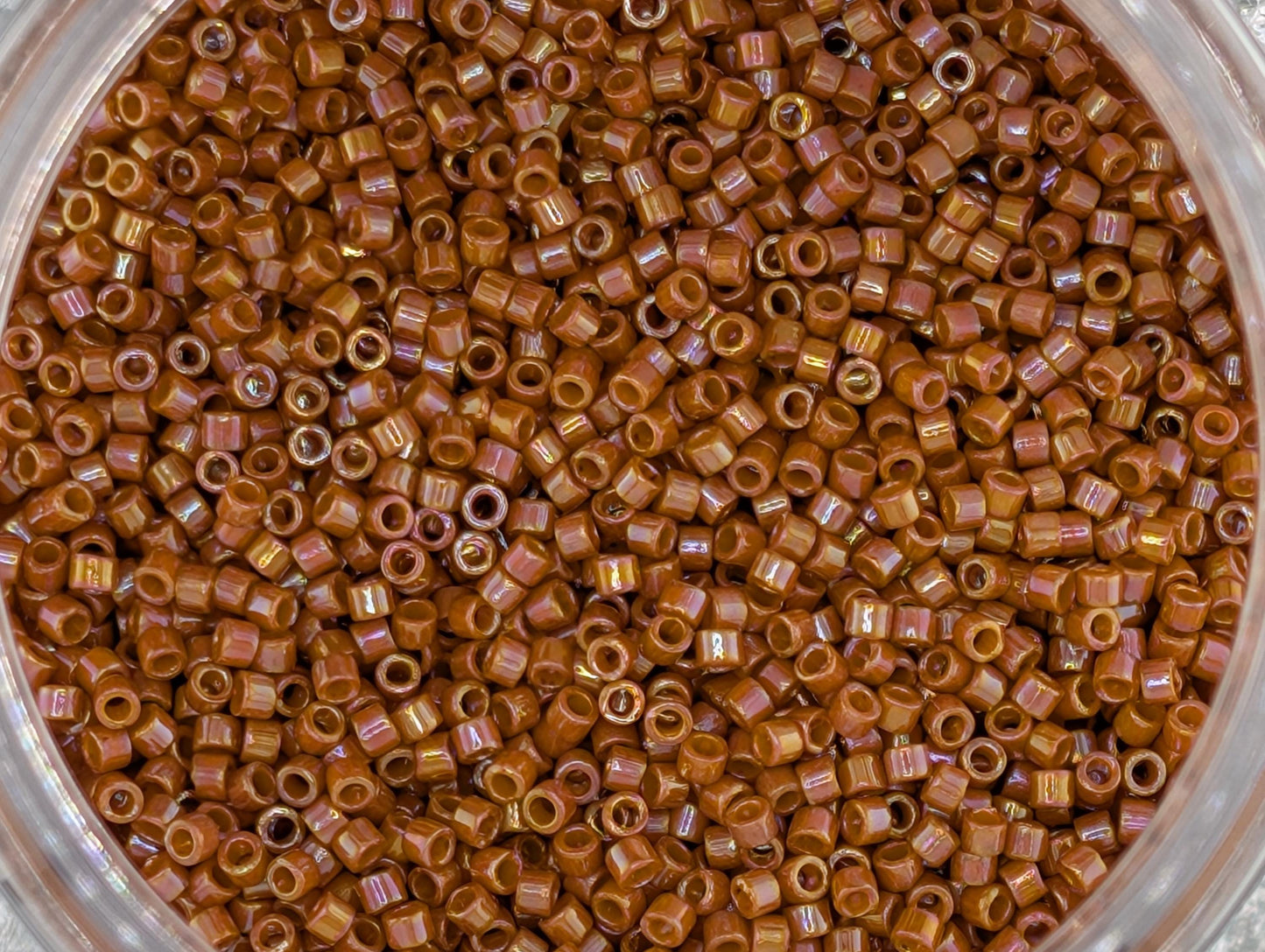 A close-up image of a glass jar filled with numerous small, brown beads or grains.