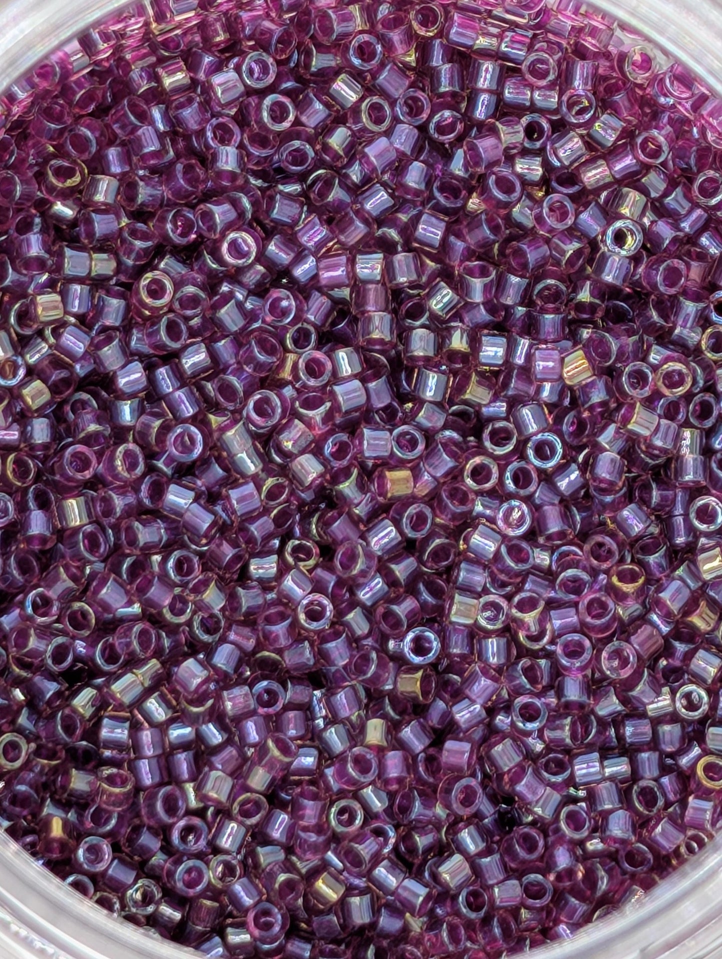 A close-up image of a container filled with numerous small, round beads in a vibrant shade of purple.