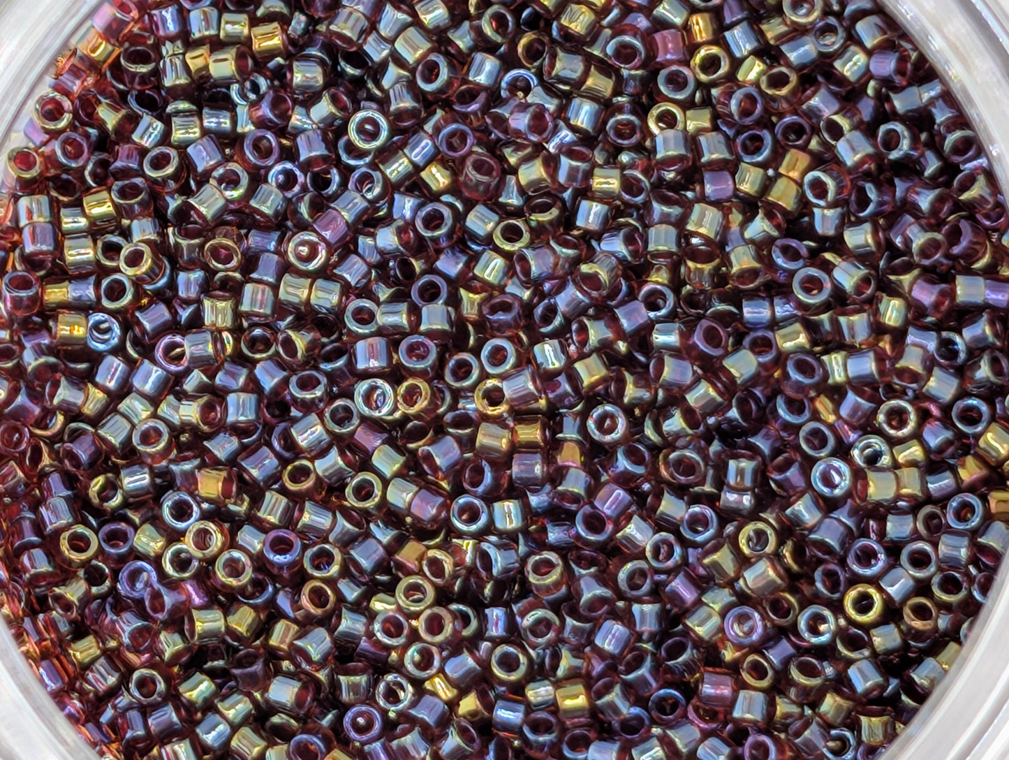 A close-up image of a container filled with multicolored beads, including shades of purple, gold, and blue.