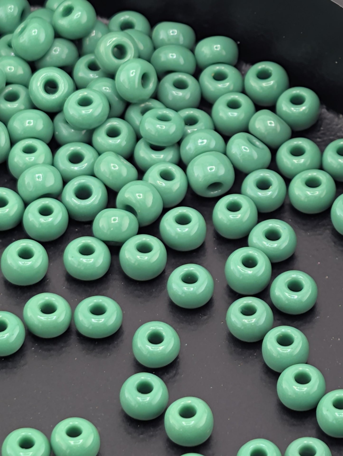 a collection of green glass beads scattered on a dark surface.