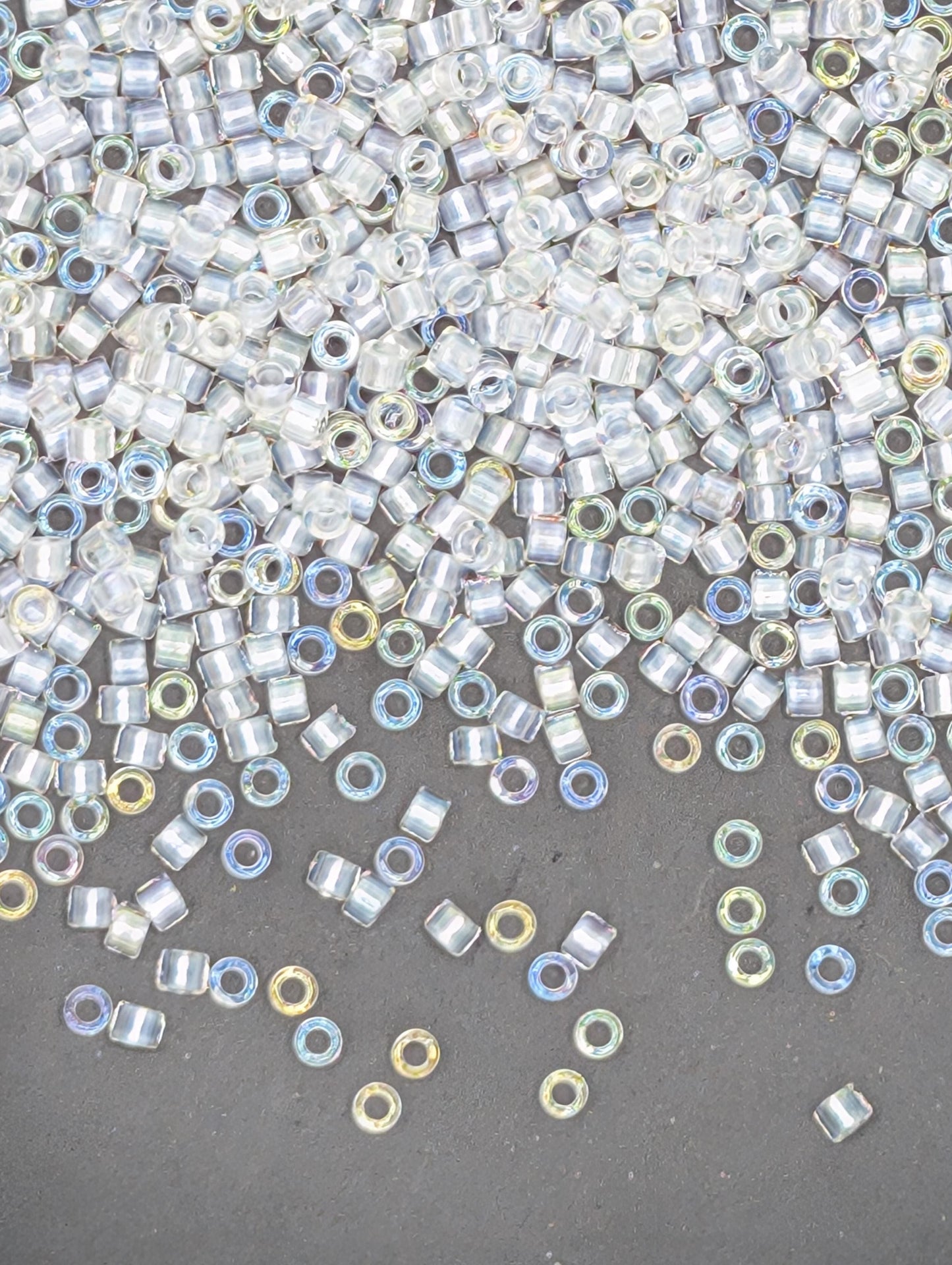 The image is a collection of numerous small, clear beads scattered across a dark surface.