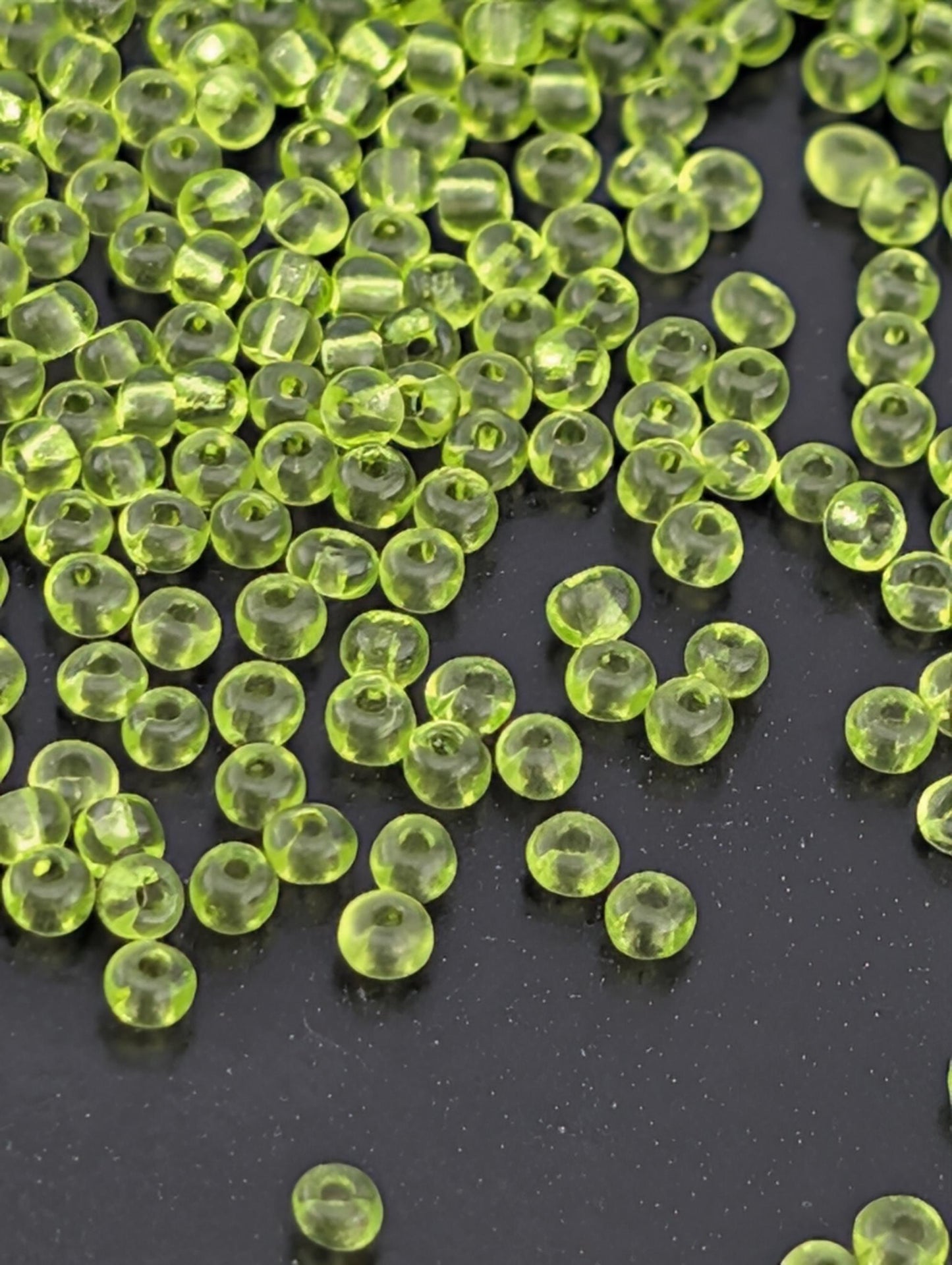 a collection of small, clear, neon green beads scattered on a dark surface.