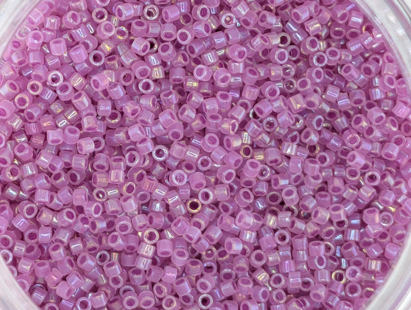 A close-up image of a pile of small, pink beads or sequins.