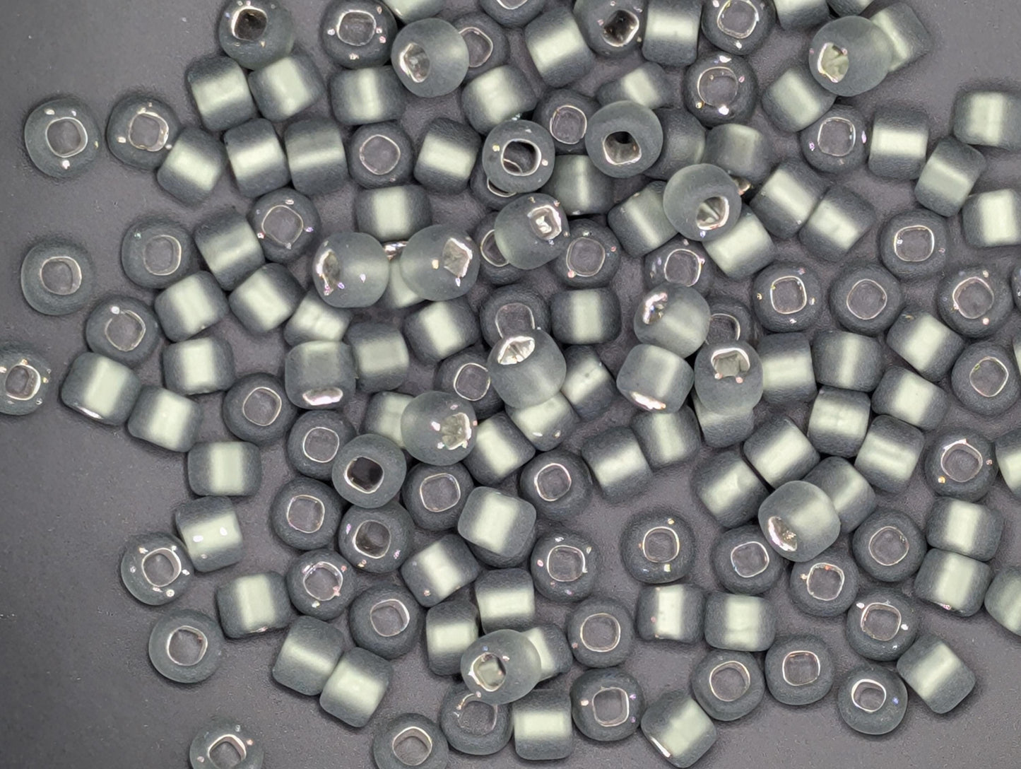 a collection of small, round beads in various shades of gray, scattered across a dark background.