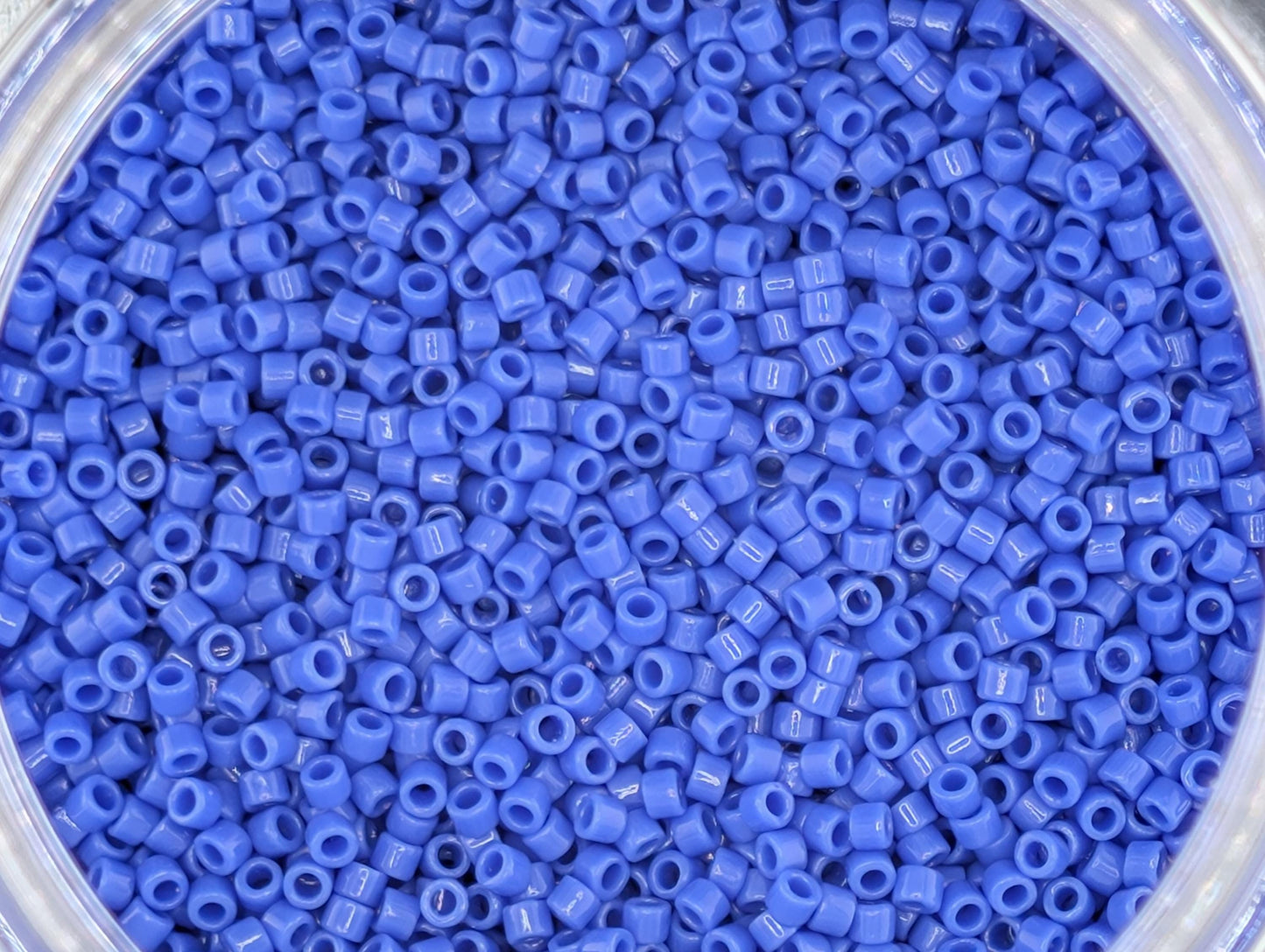 A close-up image of a container filled with numerous small, blue plastic beads.