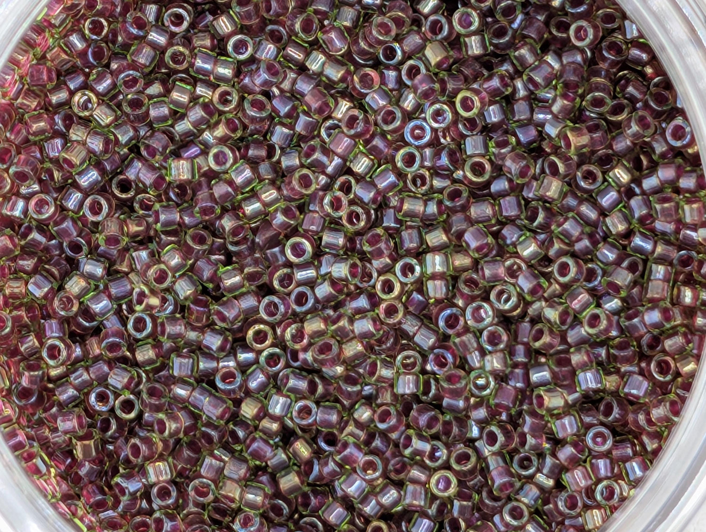 A close-up image of a large pile of small, round beads in various shades of purple and green.