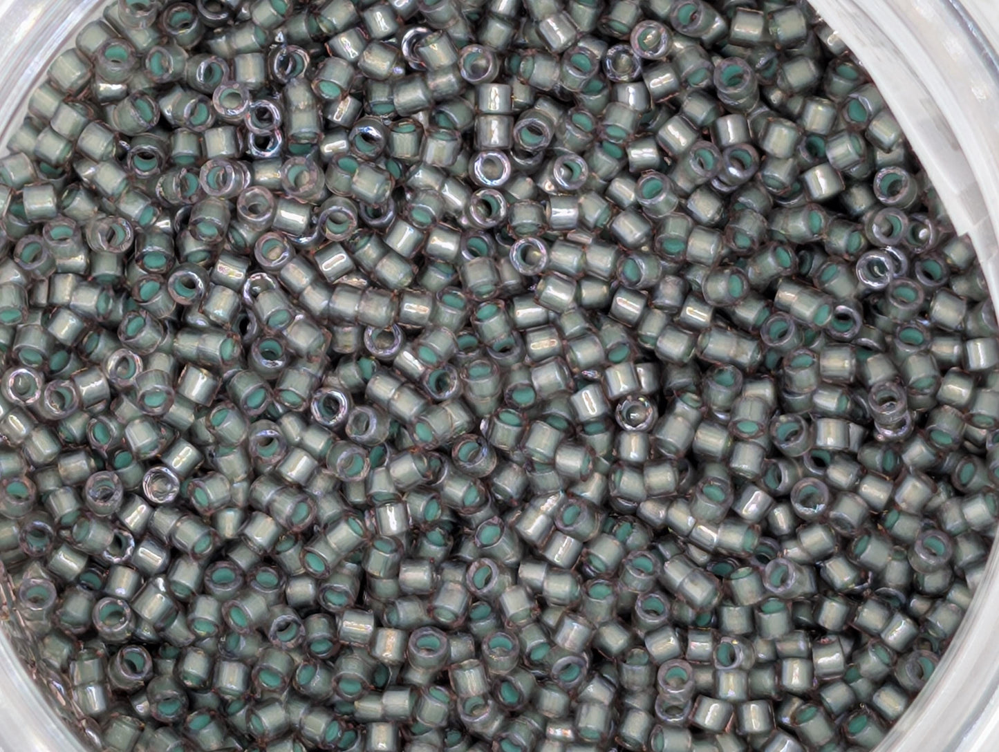 A close-up image of a large pile of small, silver-colored beads or sequins, with a variety of shapes and sizes.