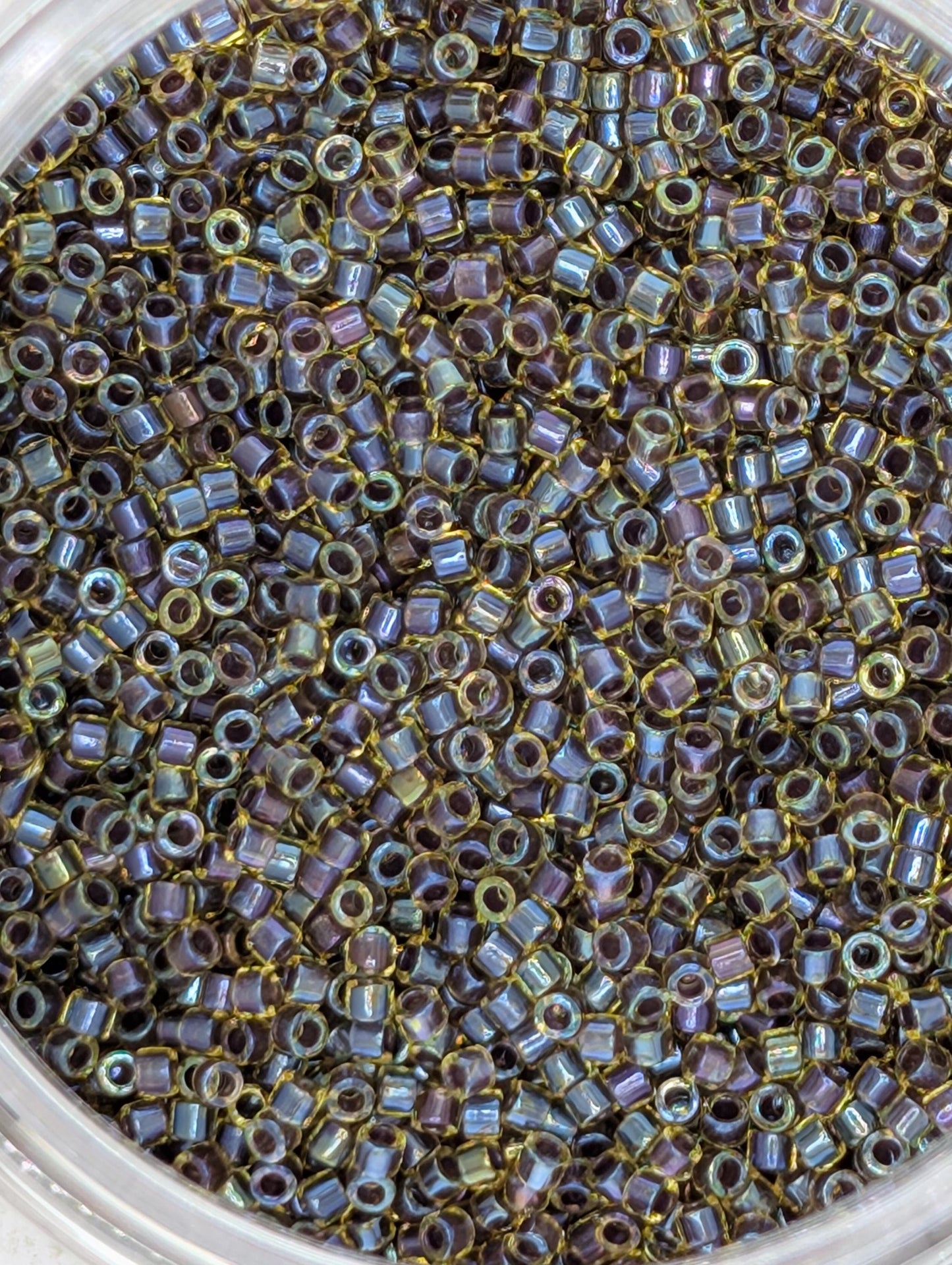 A close-up image of a container filled with numerous small, multicolored beads.
