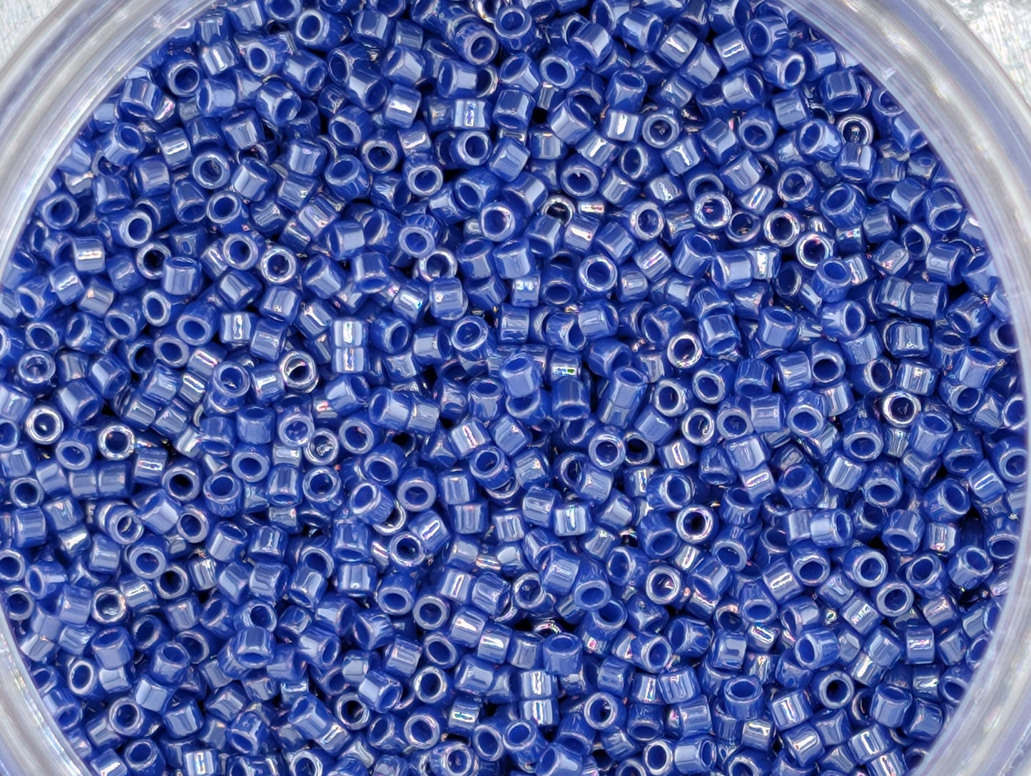 A close-up image of a container filled with numerous small blue beads.