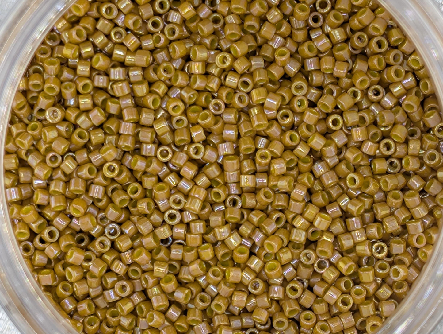 A close-up image of a container filled with small, round, yellow beads or grains.