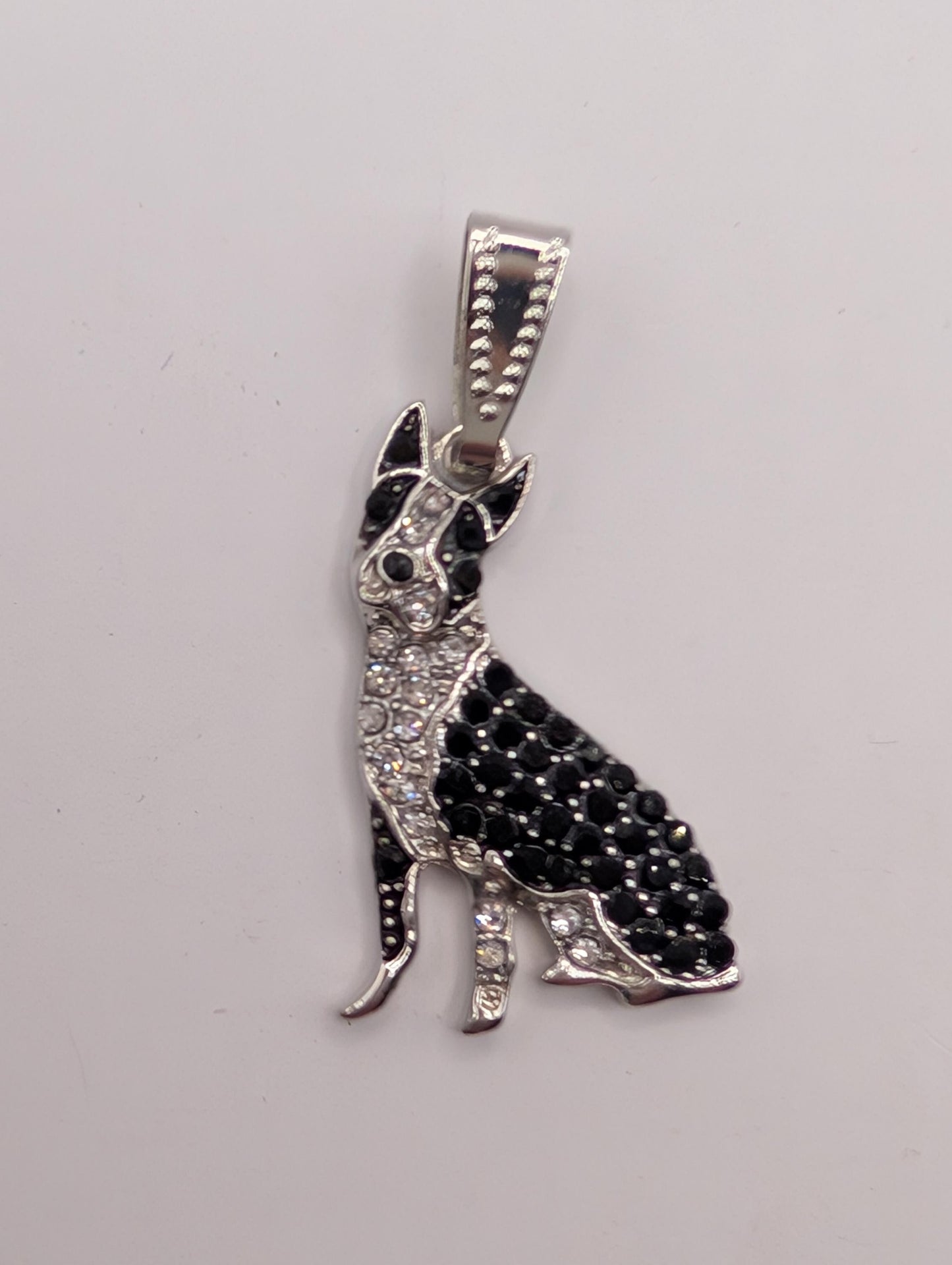 A silver-toned pendant in the shape of a dog, adorned with black and white diamonds.