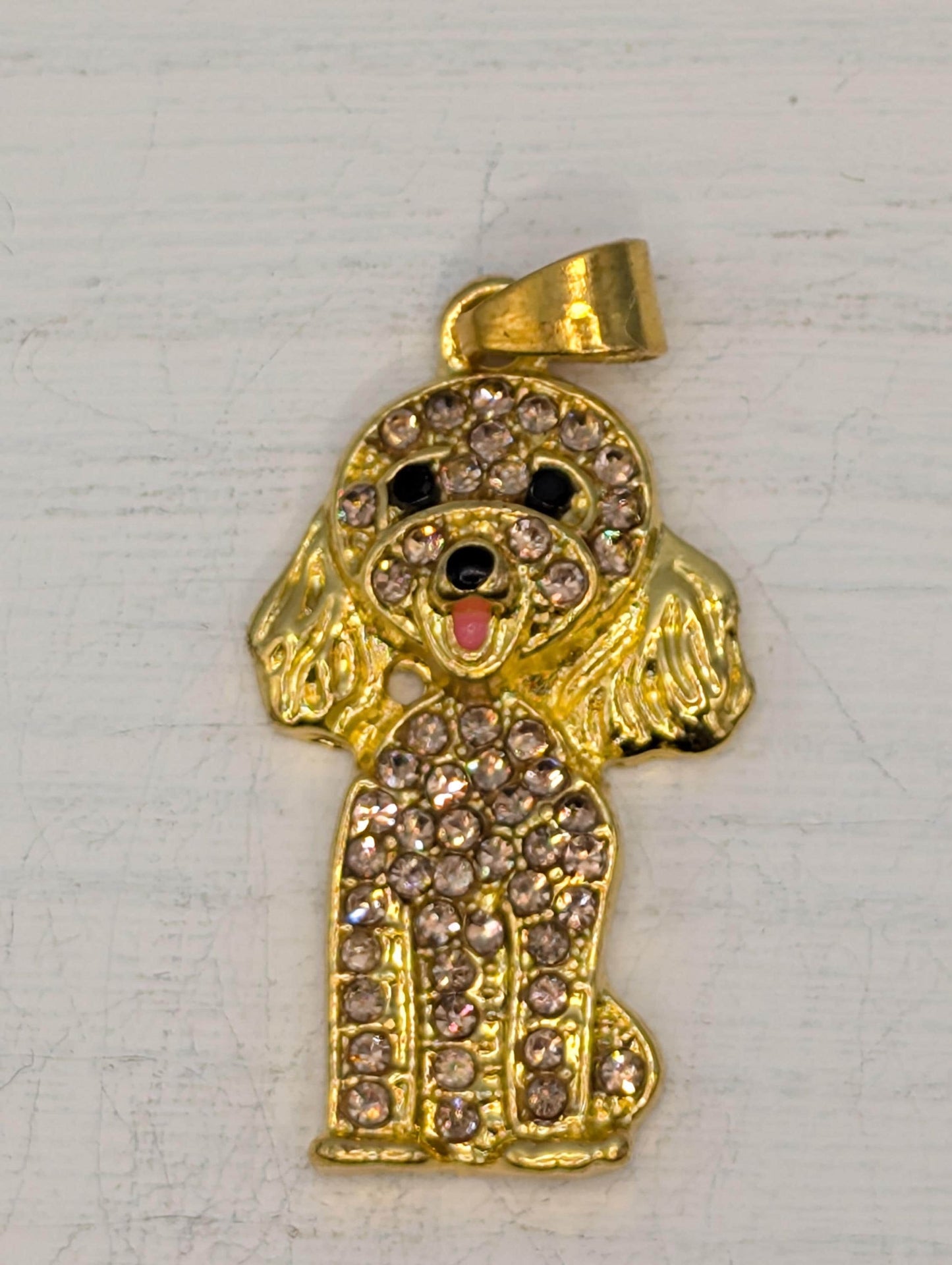 A gold-colored pendant in the shape of a dog, adorned with numerous small diamonds.
