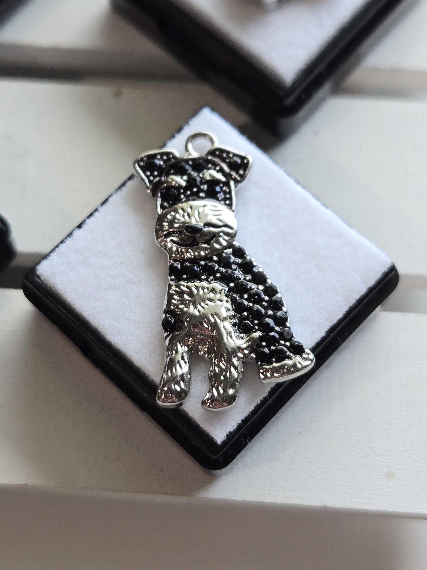 A decorative metal object with a black and silver design, featuring a small animal or creature, is displayed on a white surface.