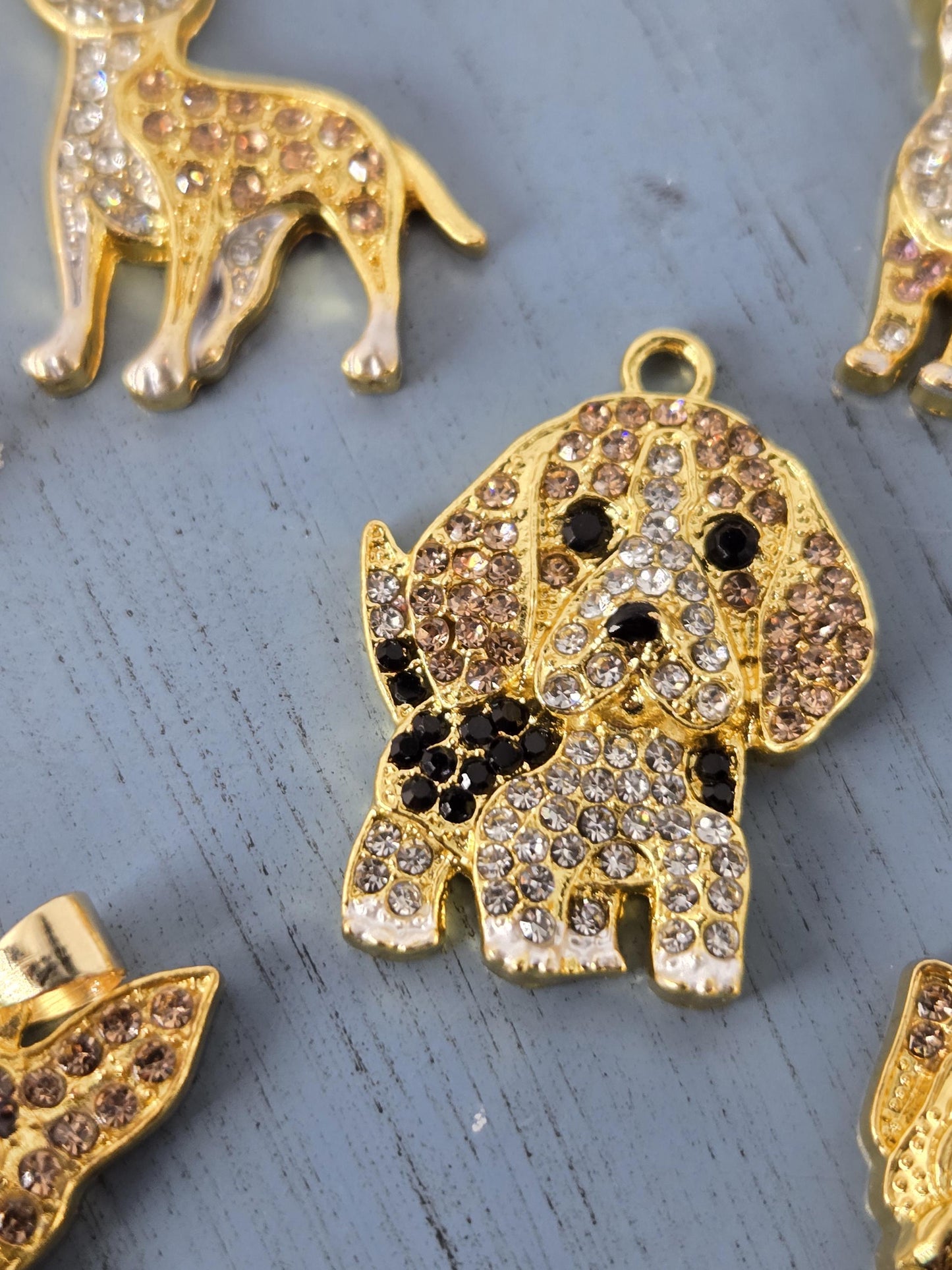 a close-up view of several ornate, gold-colored charms or pendants adorned with sparkling rhinestones or crystals.