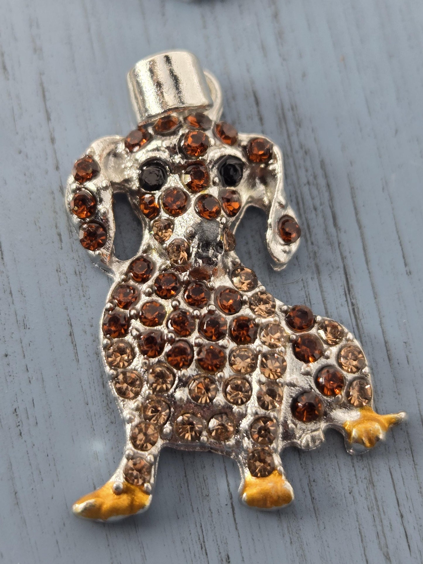 A decorative metal pin with a dog-like design, featuring a combination of brown and gold gemstones.