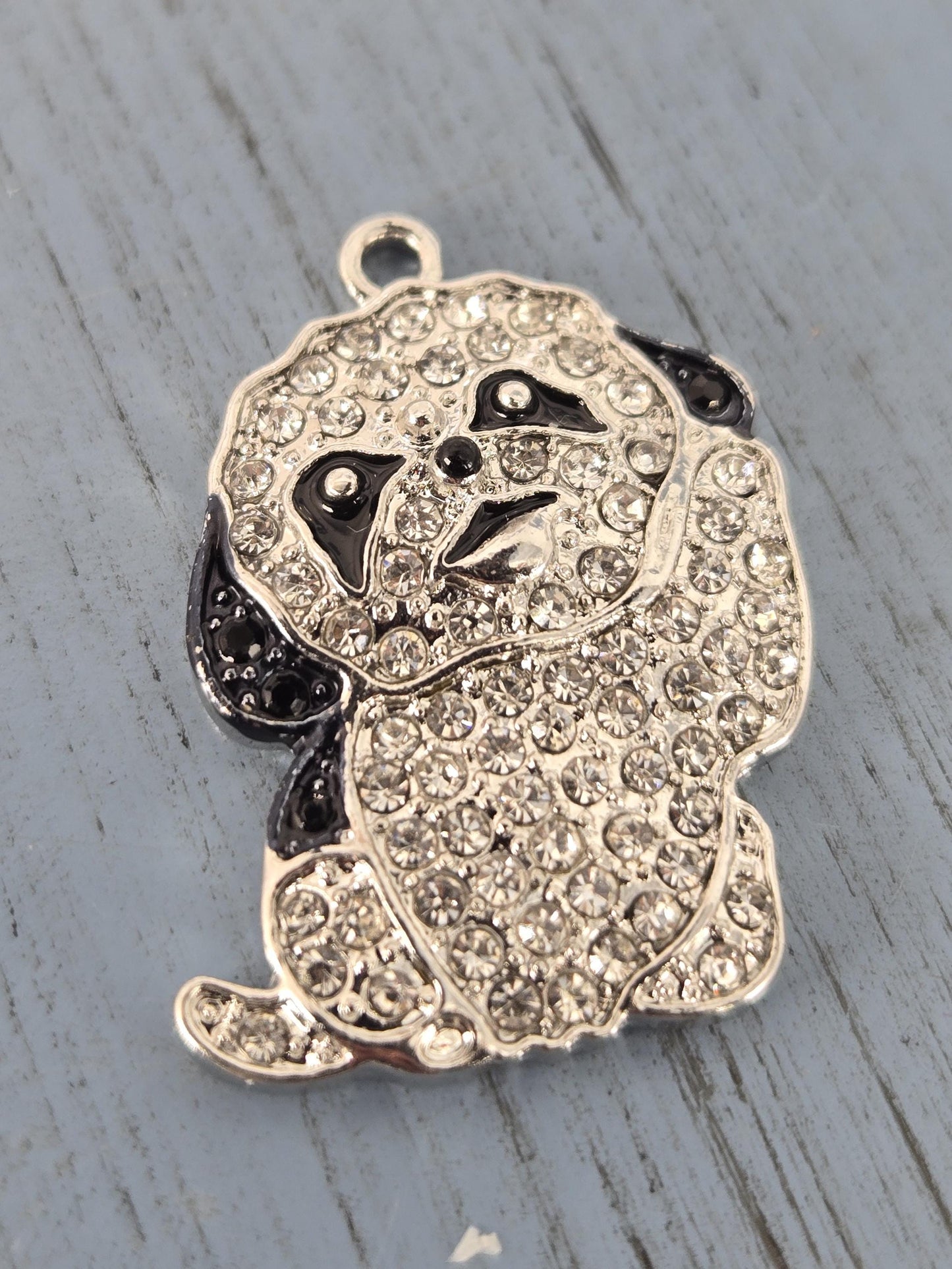 A silver-colored panda charm adorned with numerous sparkling rhinestones.