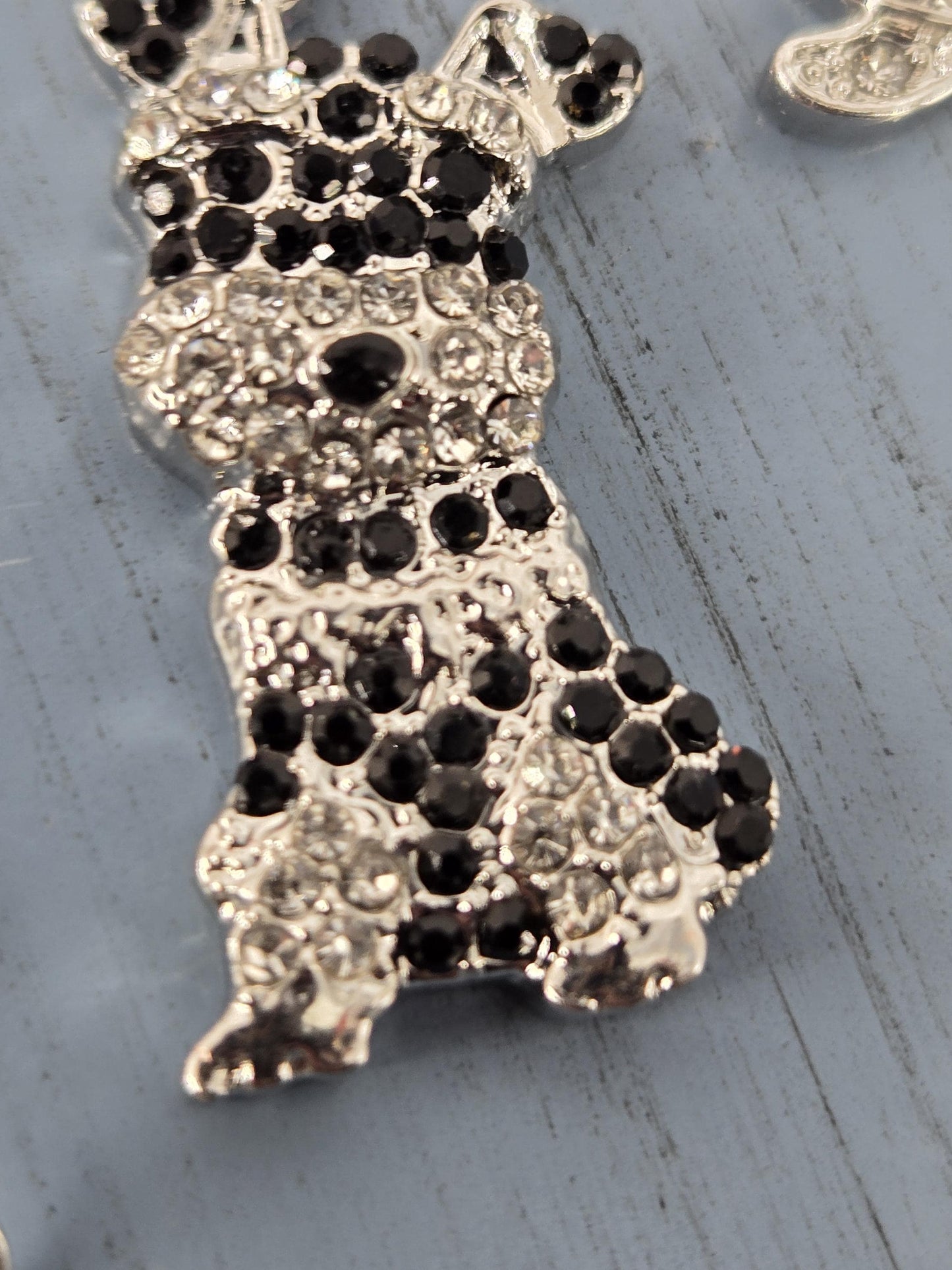 A close-up image of a decorative piece with a silver-colored metal surface adorned with numerous black and white gemstones.
