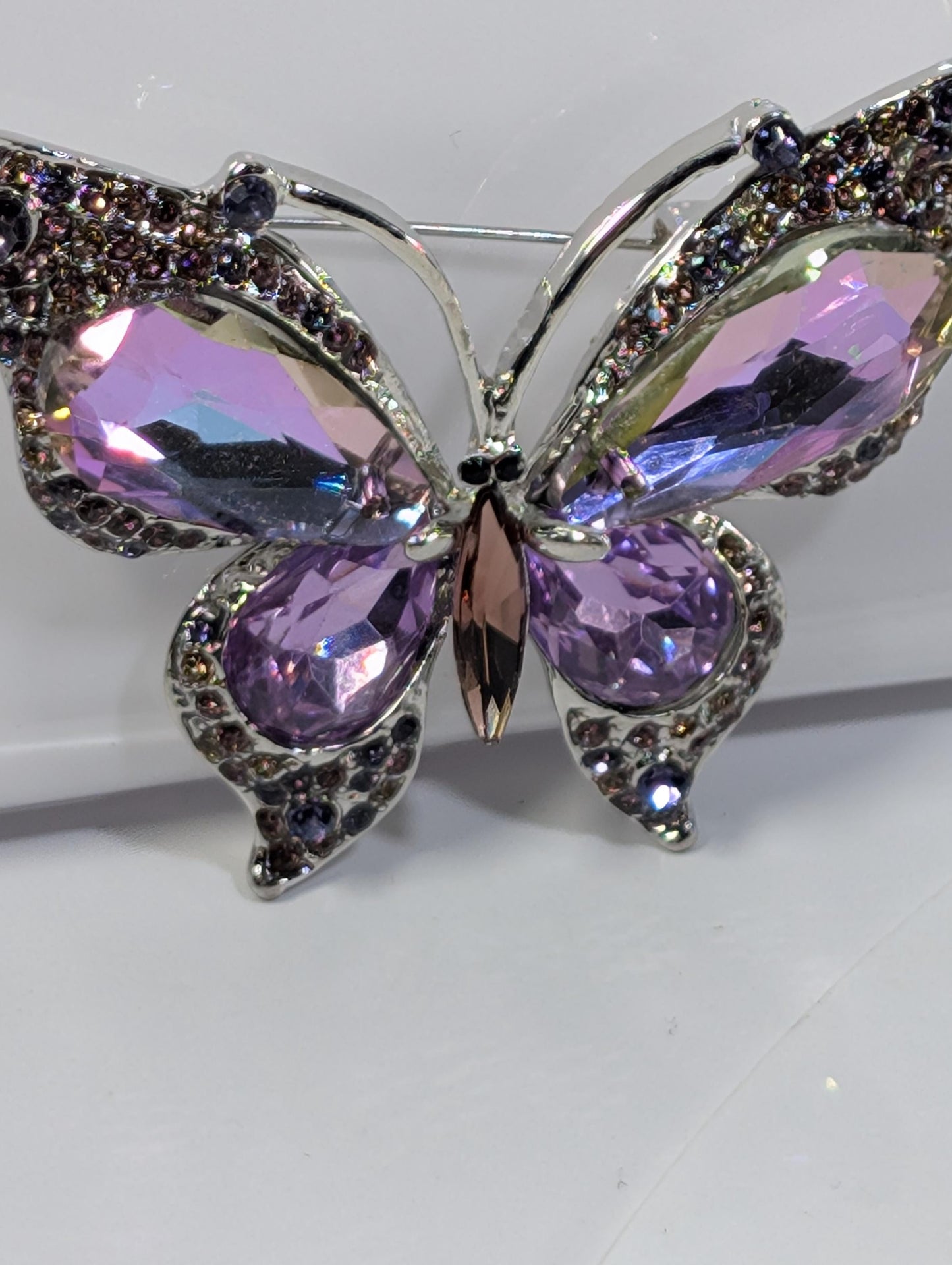 A decorative butterfly brooch with purple gemstones and intricate metalwork.