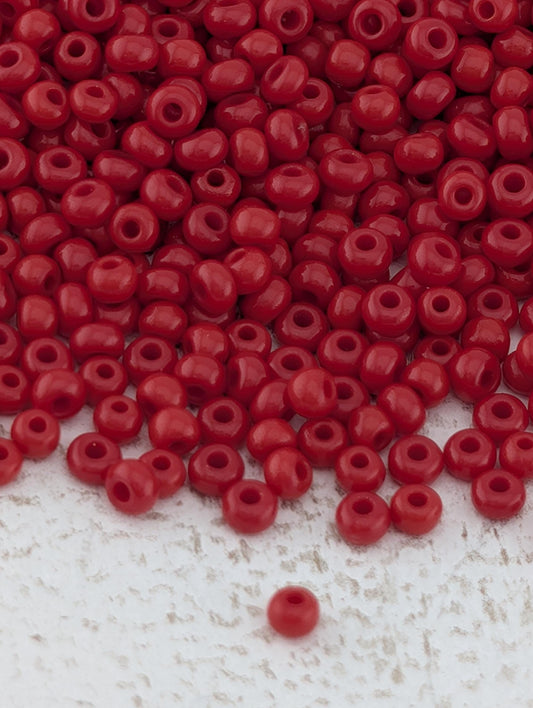 a large pile of red beads scattered on a white surface.