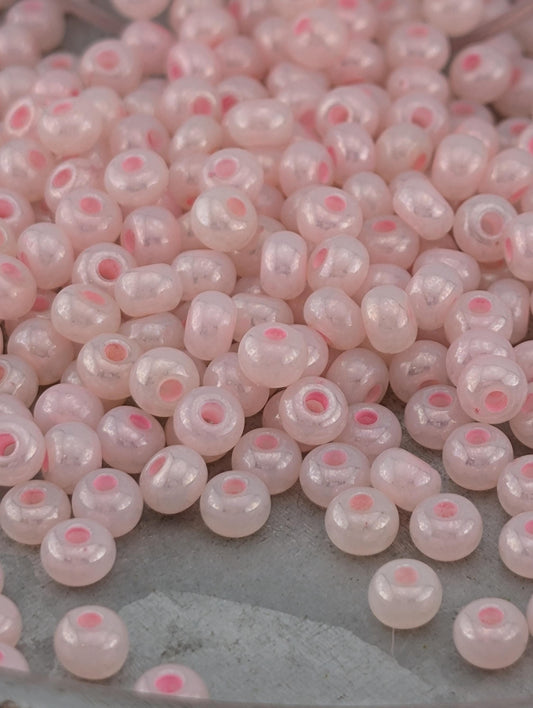 a close-up view of numerous small, round beads in shades of pink and white, scattered across a surface.
