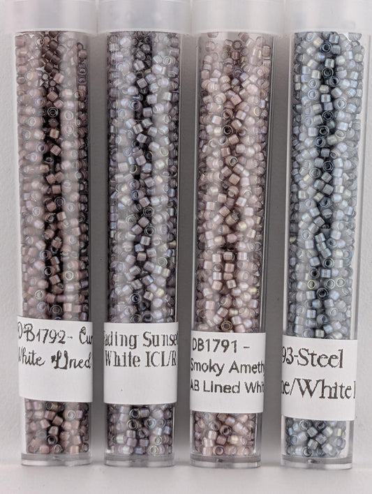 four transparent glass containers filled with beads of different colors, including white, black, and silver.