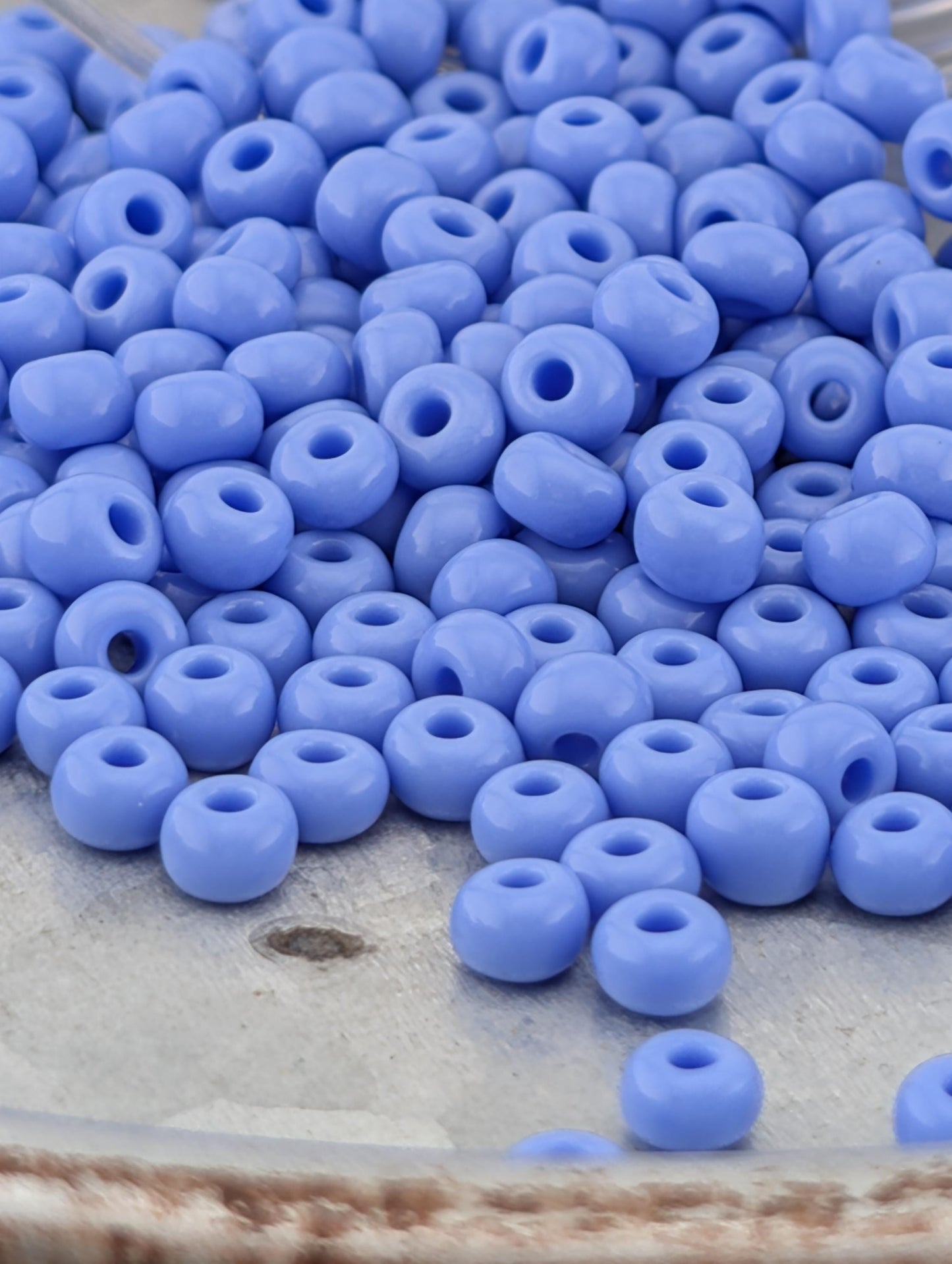 A pile of small, round, blue beads on a surface.