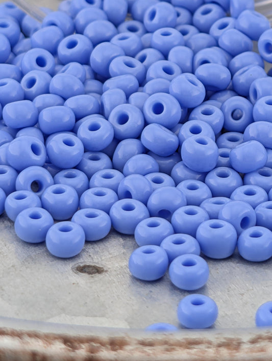 A pile of small, round, blue beads on a surface.
