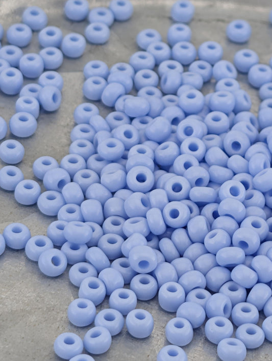 a large pile of small, light blue beads scattered on a surface.