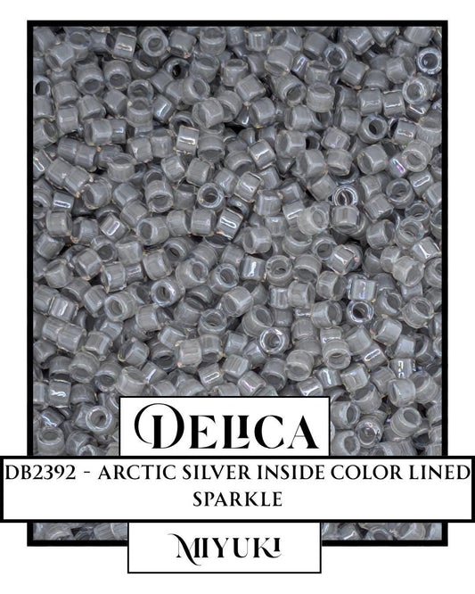 The image is a close-up of numerous small, clear beads or grains, possibly silver or metallic, arranged in a visually appealing manner.