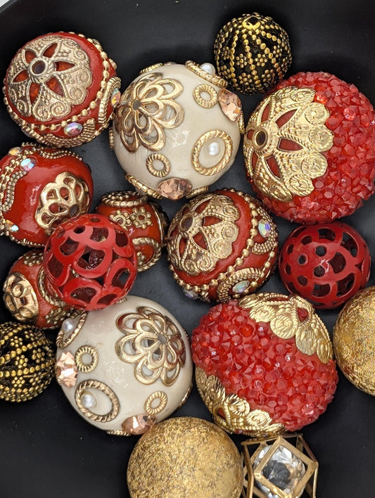 a collection of ornate, decorative objects, including balls, beads, and other embellishments, arranged on a black surface.