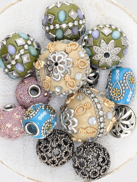 a collection of ornate, colorful beads and jewelry pieces, including various shapes and sizes, arranged on a white surface.