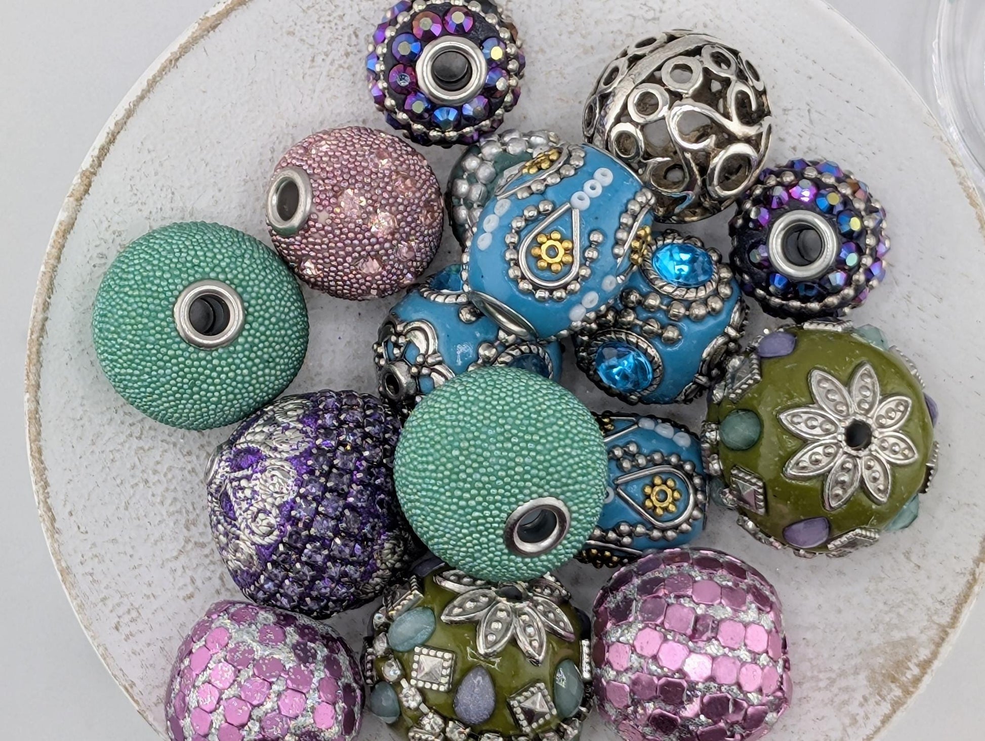 a collection of colorful beads and jewelry pieces, including various shapes and sizes, arranged on a white surface.