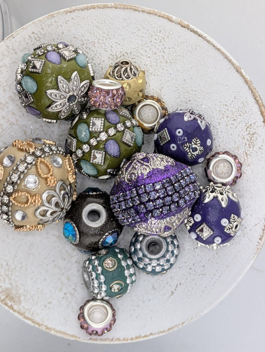 a collection of ornate, colorful beads and jewelry pieces arranged on a white plate or bowl.