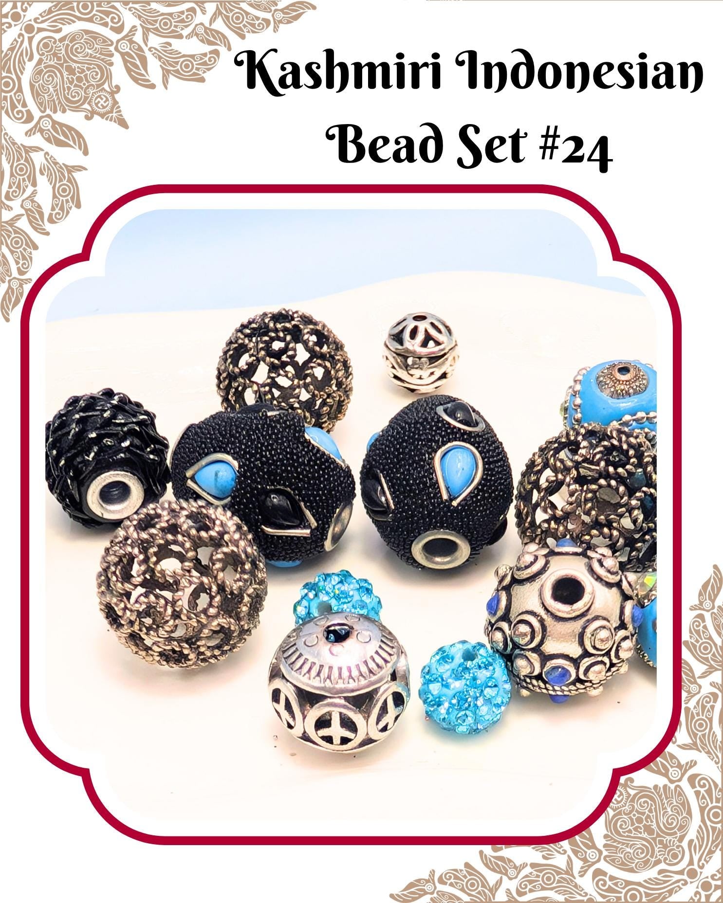 a collection of various beads, including black, blue, and silver beads, arranged on a white surface.