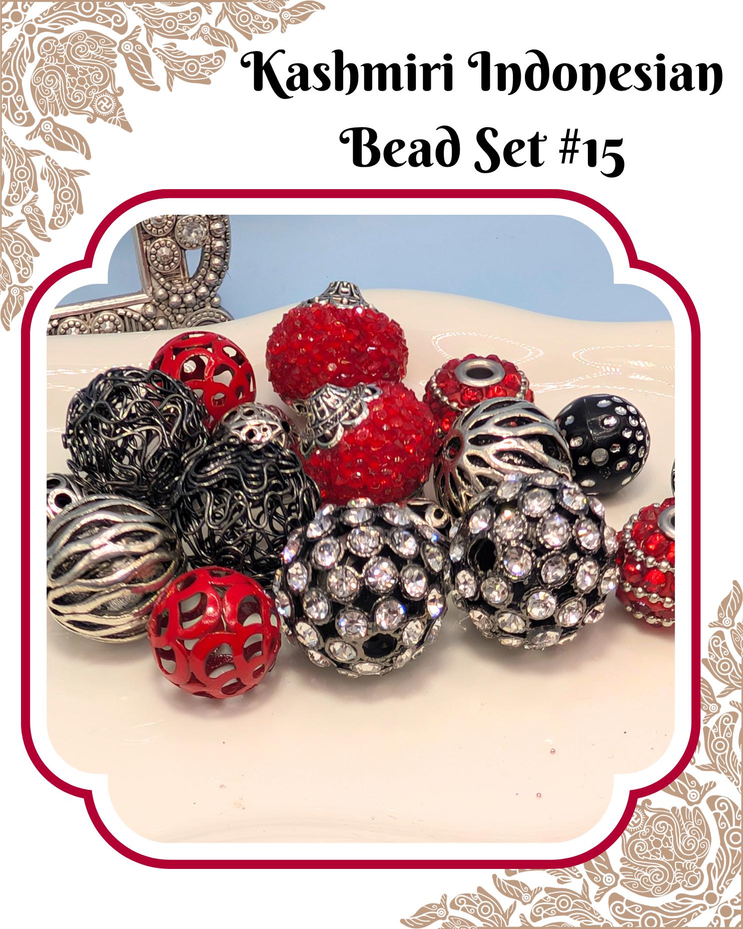 A collection of colorful beads, including red, black, silver, and crystal balls, arranged on a white surface.