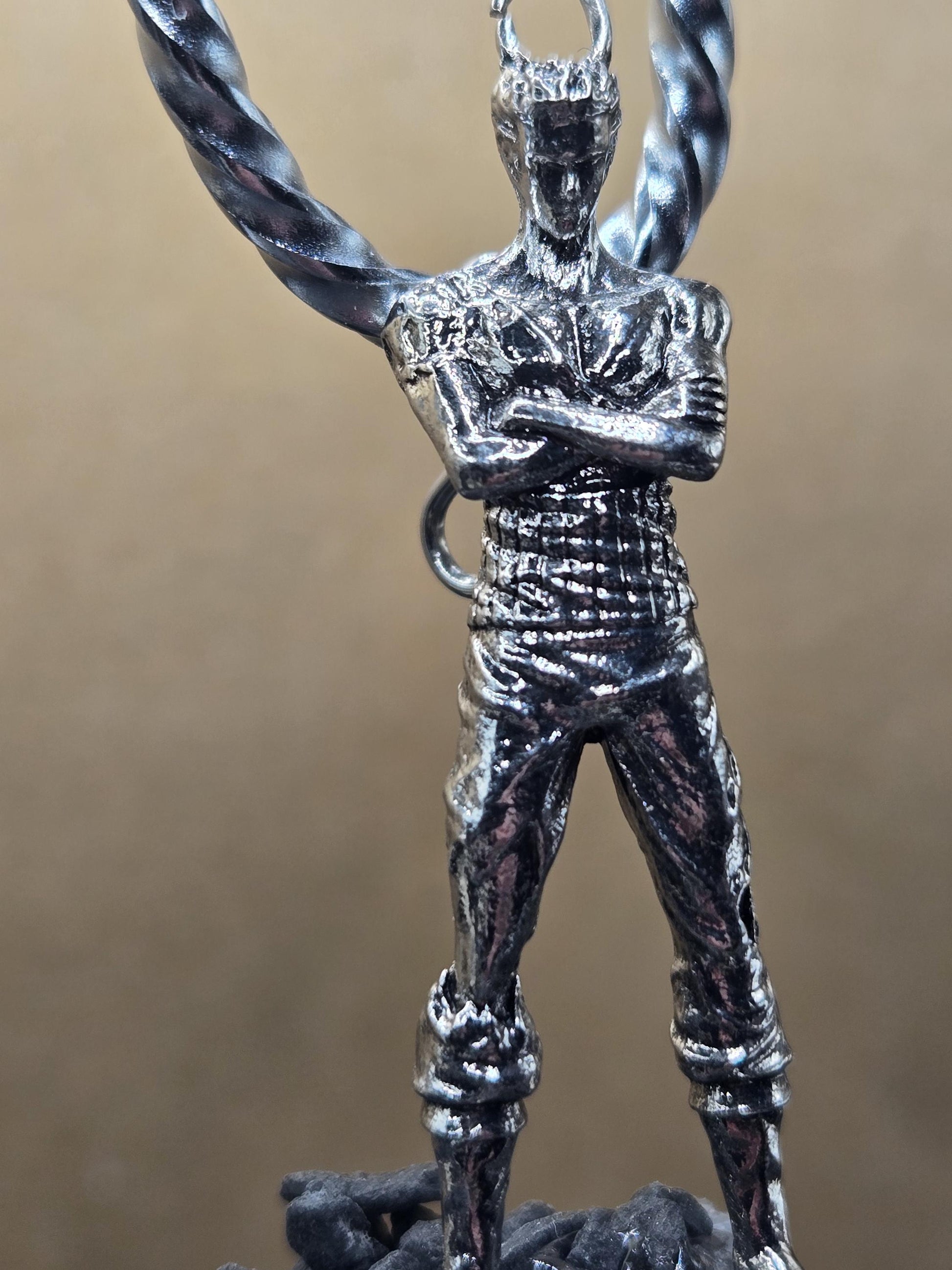 A close-up view of a silver-colored metal object, possibly a piece of jewelry or a decorative item, with a textured surface and a twisted or braided design.