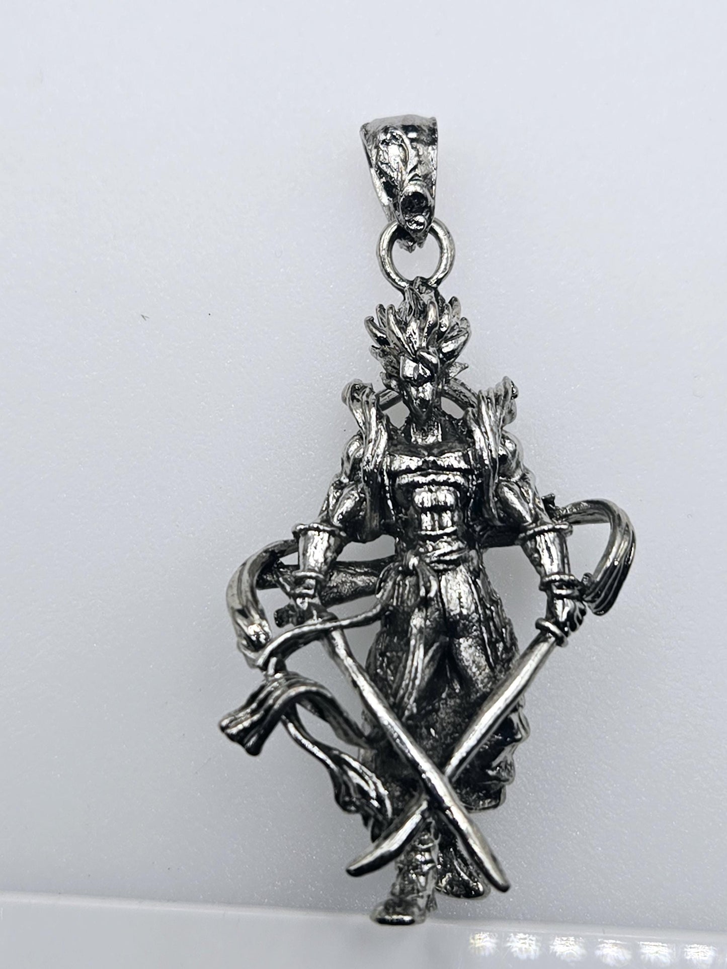 A silver-colored pendant in the shape of a sword, with intricate details and a decorative design.