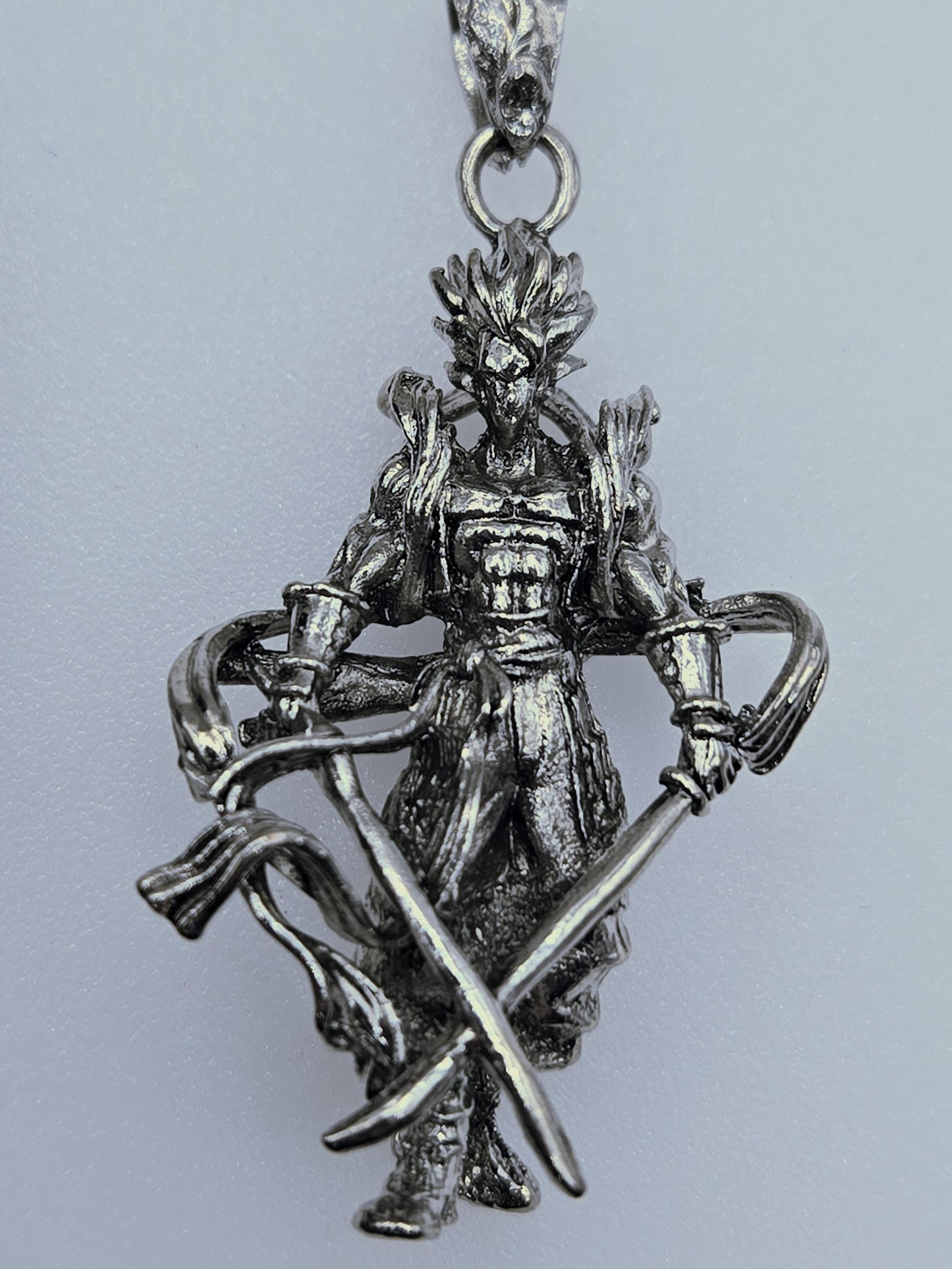 A silver-colored metal pendant or charm in the shape of a dragon or mythical creature, with intricate details and designs.