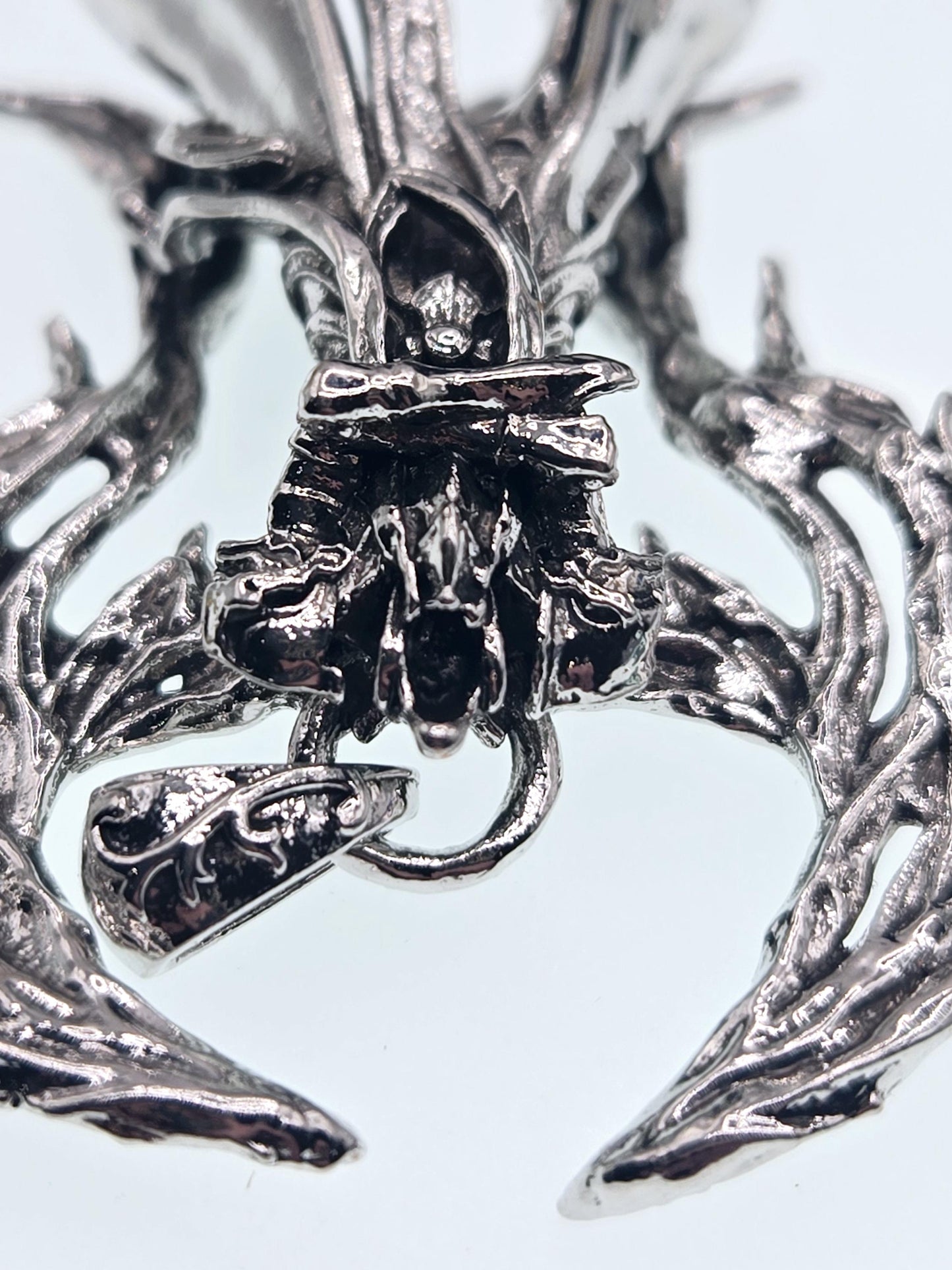 The image is a close-up of a metallic, sculptural piece with intricate, organic-looking textures and patterns.