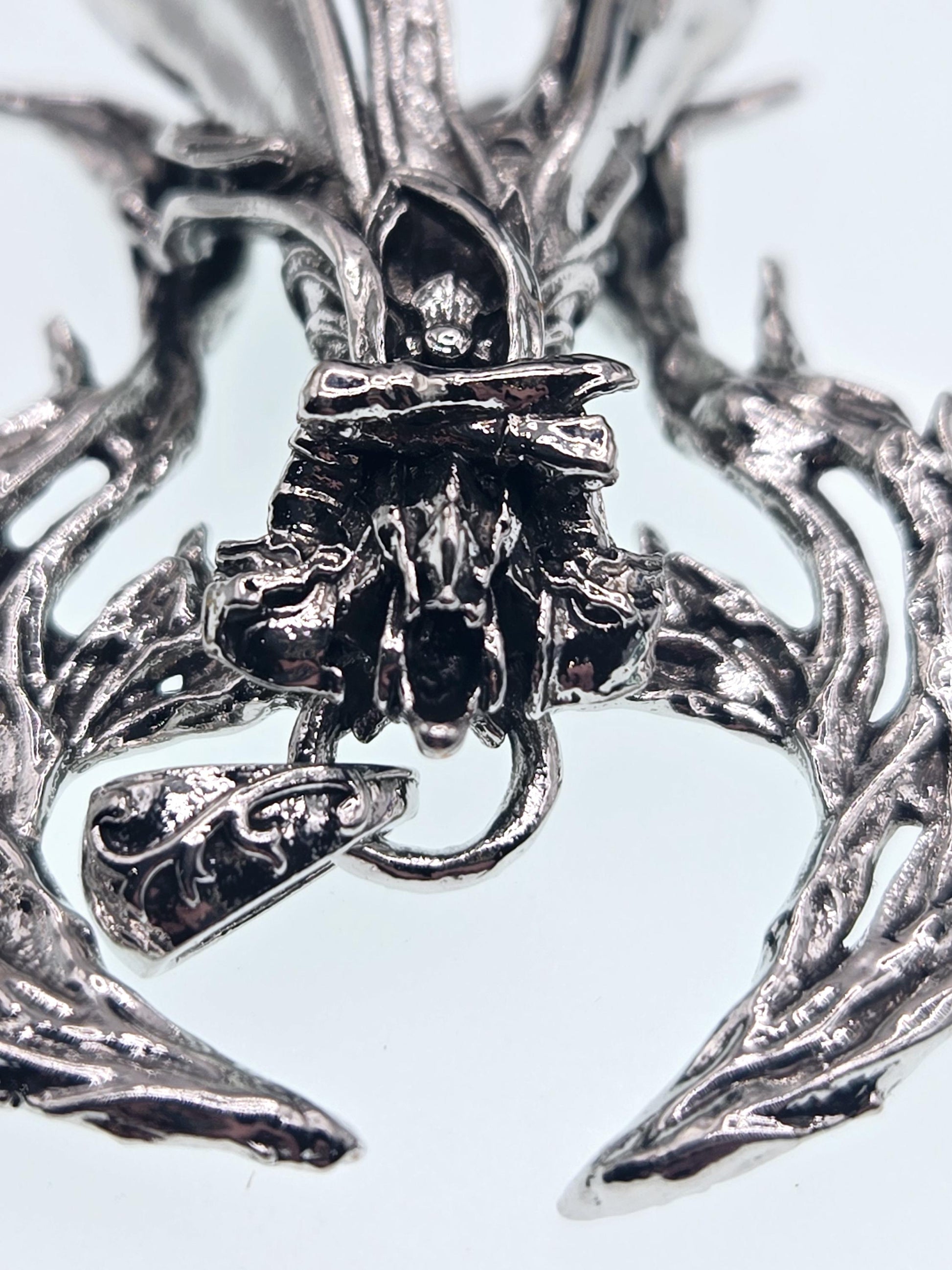 The image is a close-up of a metallic, sculptural piece with intricate, organic-looking textures and patterns.