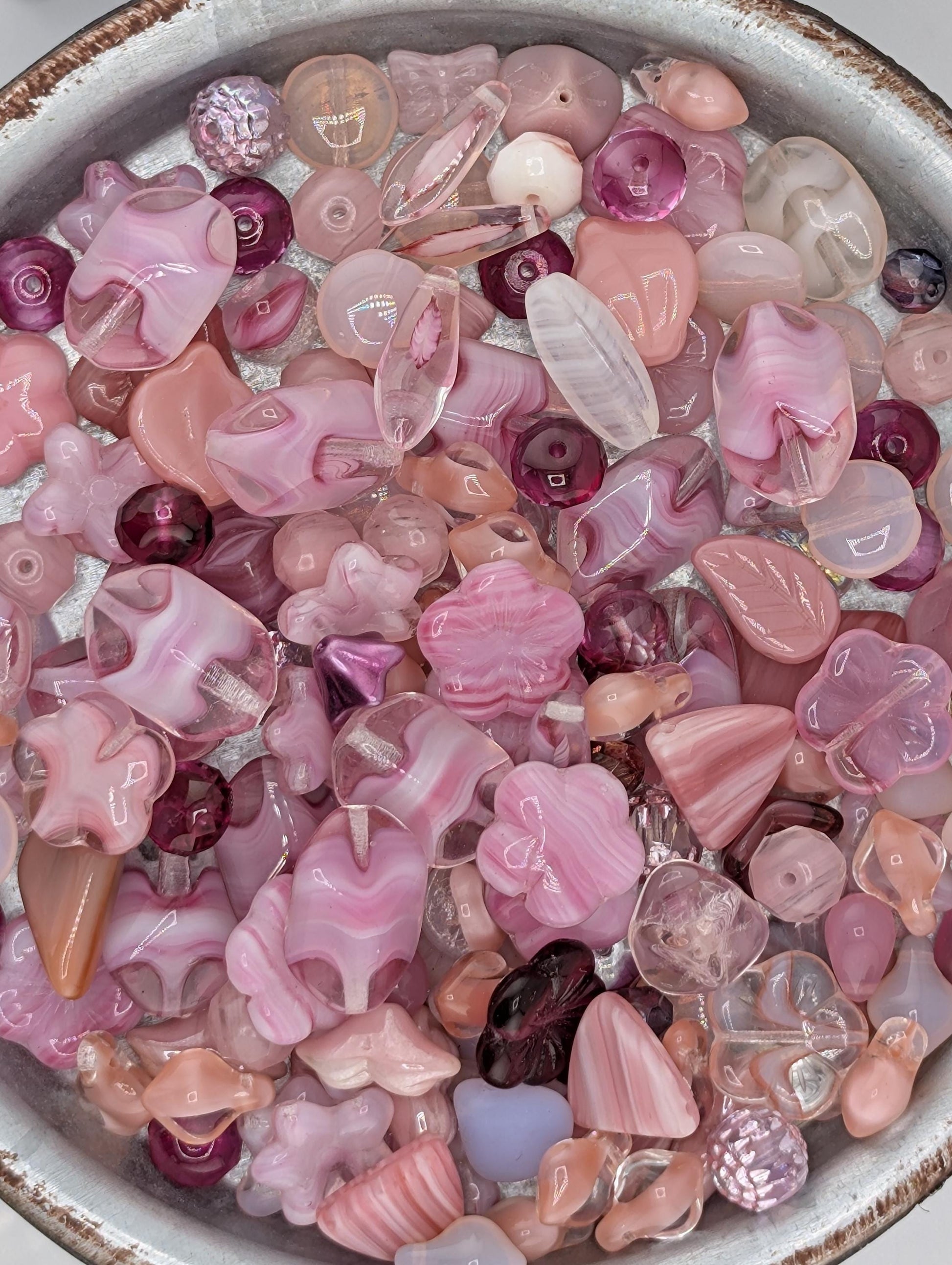 A bowl filled with various colorful glass beads in shades of pink and purple.