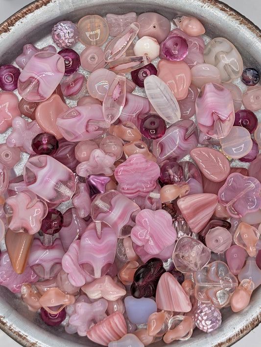A bowl filled with various colorful glass beads in shades of pink and purple.