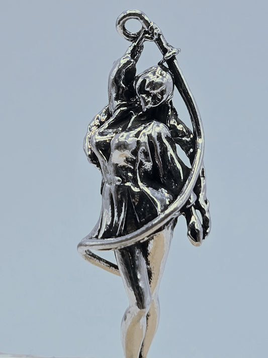 A close-up view of a silver-colored metal sculpture depicting a figure in a dynamic pose, with a curved arm and a flowing, abstract design.