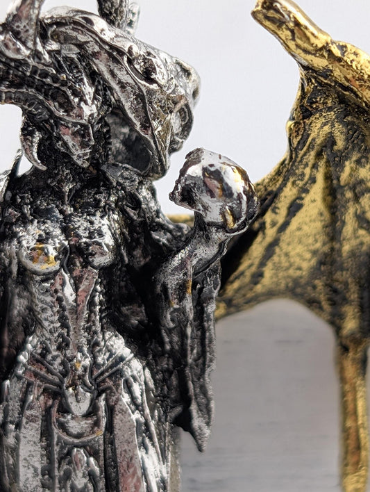 a detailed metal sculpture of a woman with a skull in her hand.