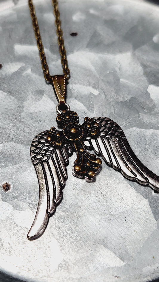 A close-up view of a decorative metal pendant with a wing design, attached to a chain.