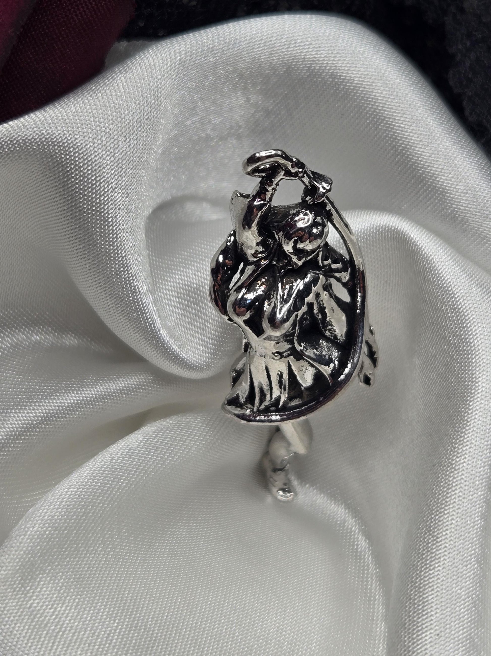 A silver-colored metal object, possibly a ring or a decorative piece, is resting on a white fabric surface.