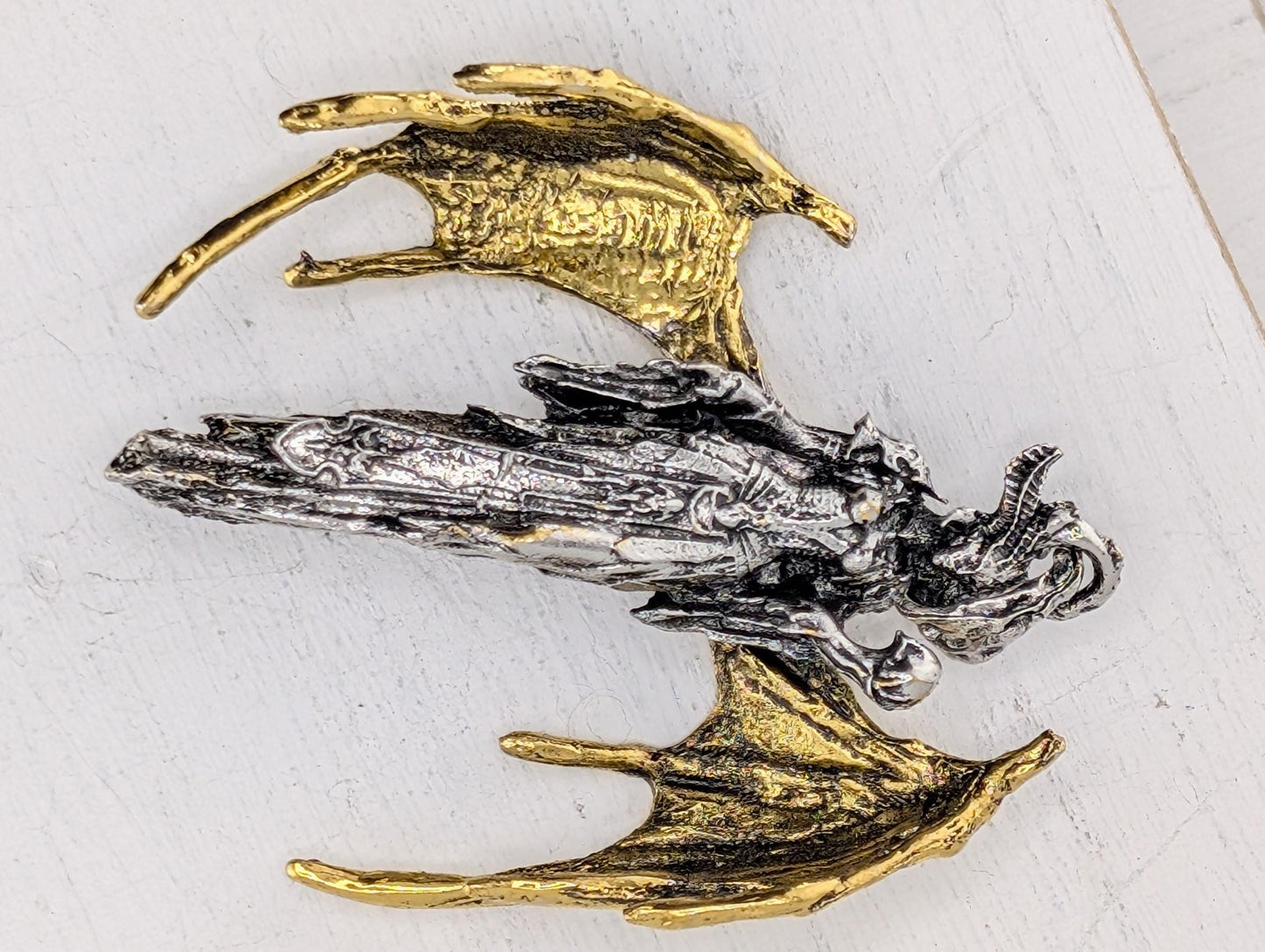 a detailed metal sculpture of a dragon-like creature with intricate wings and a fierce expression.