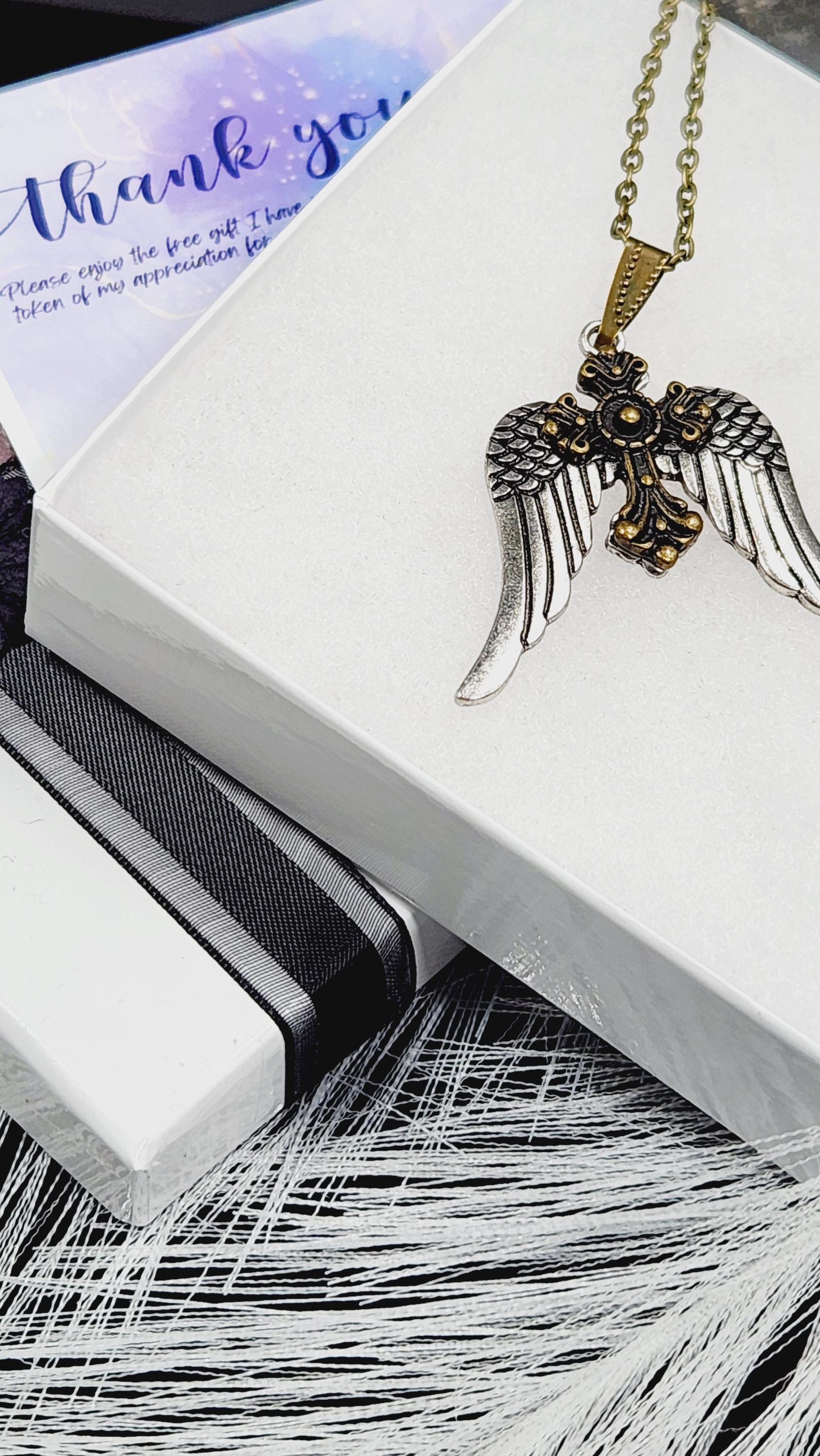 A white box with a gold cross pendant and a feather-like object on top, along with a purple card with text.
