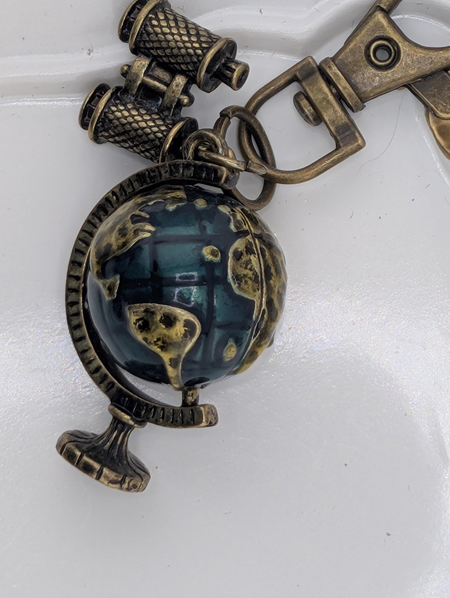 A decorative keychain with a globe and a pair of binoculars attached to it.