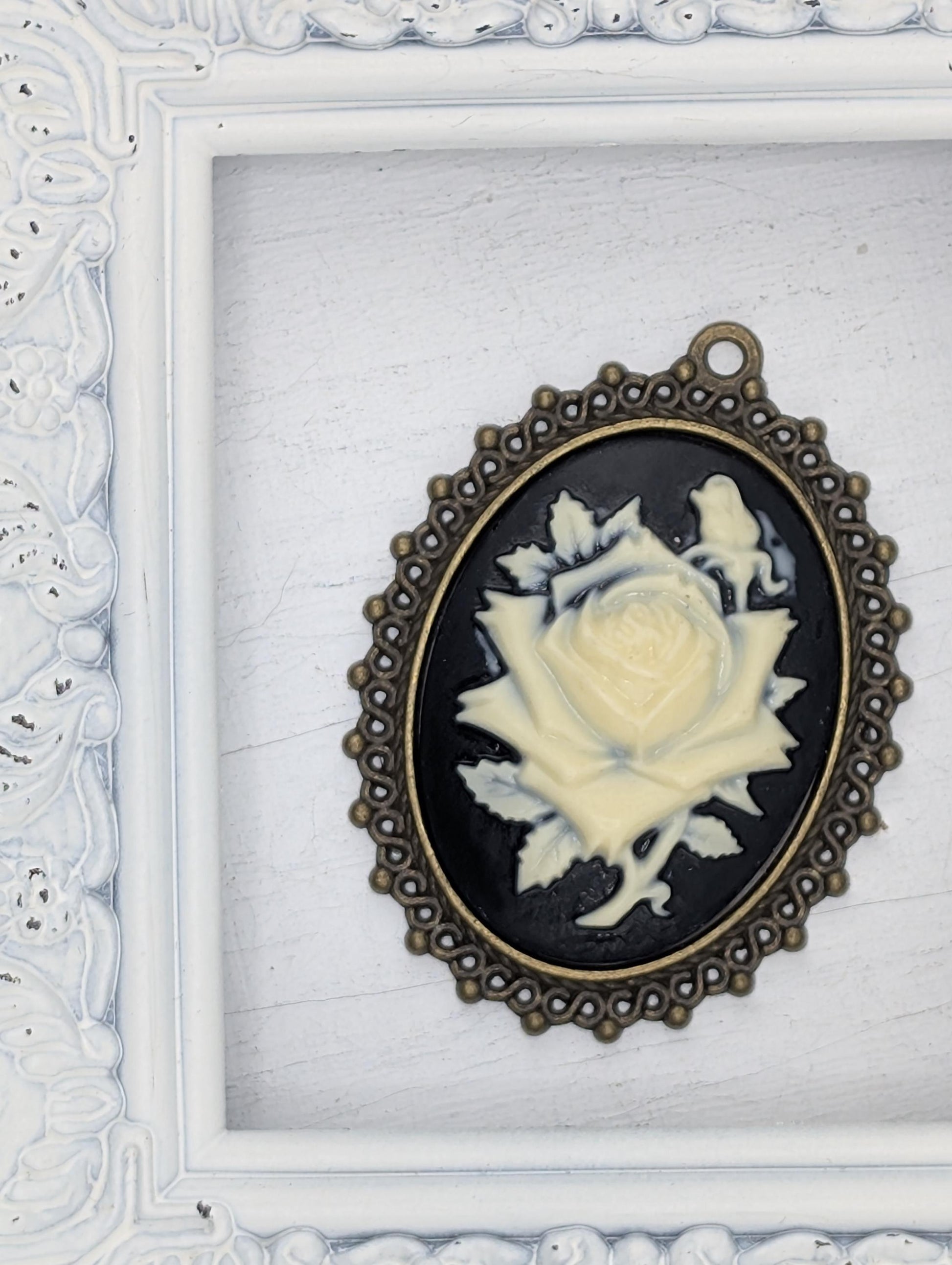 A white oval-shaped frame with a black background and a gold-colored metal frame around it, containing a white rose-shaped object with a black background.